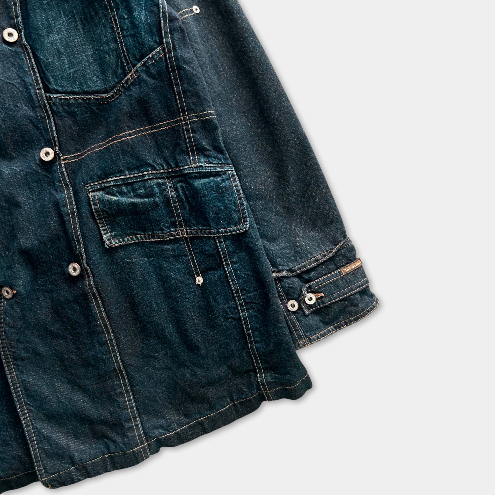 A close-up view of a dark blue denim jacket with multiple pockets and buttons.