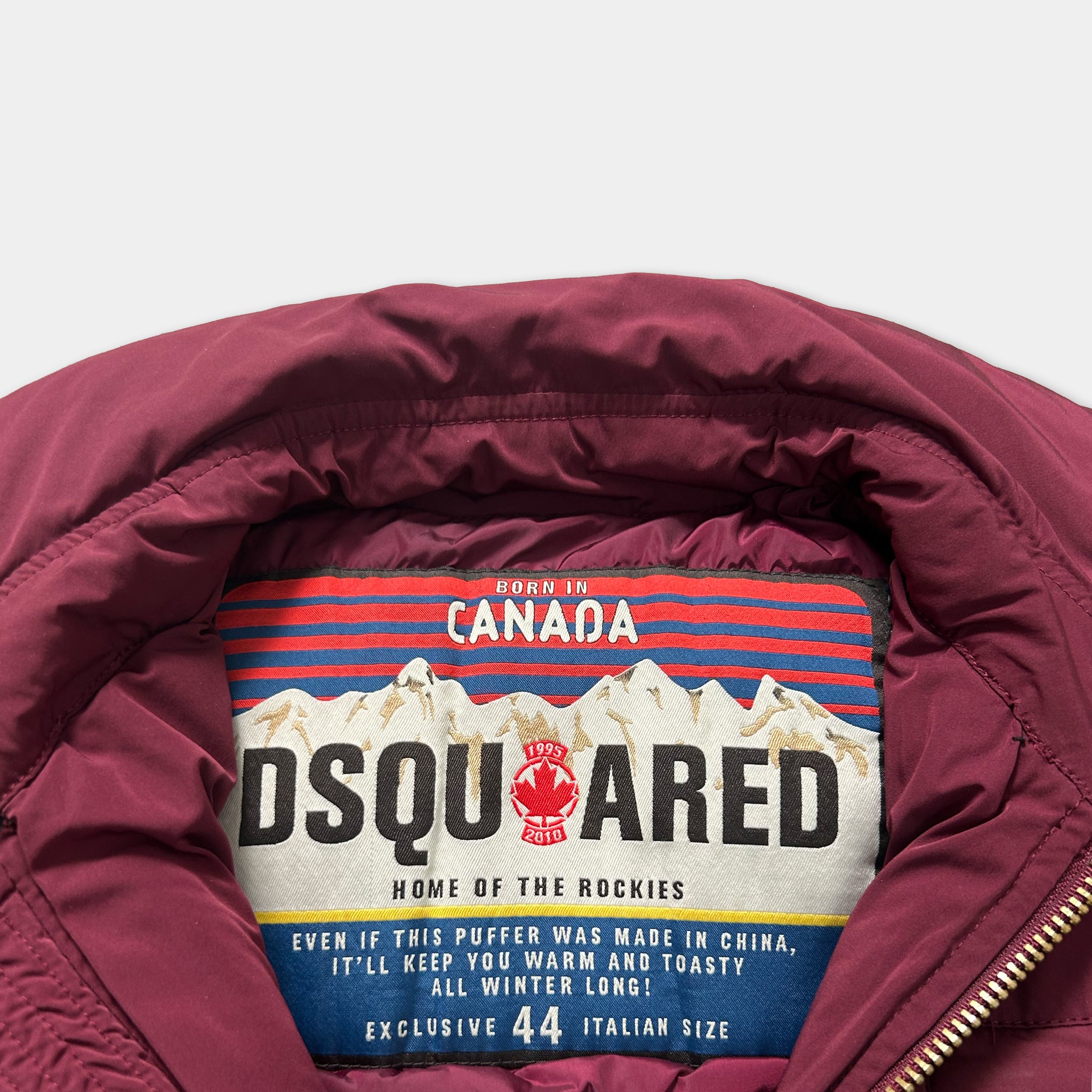 a close-up view of a burgundy-colored jacket with a label that displays the DQUARED brand name and the text "Home of the Rockies".