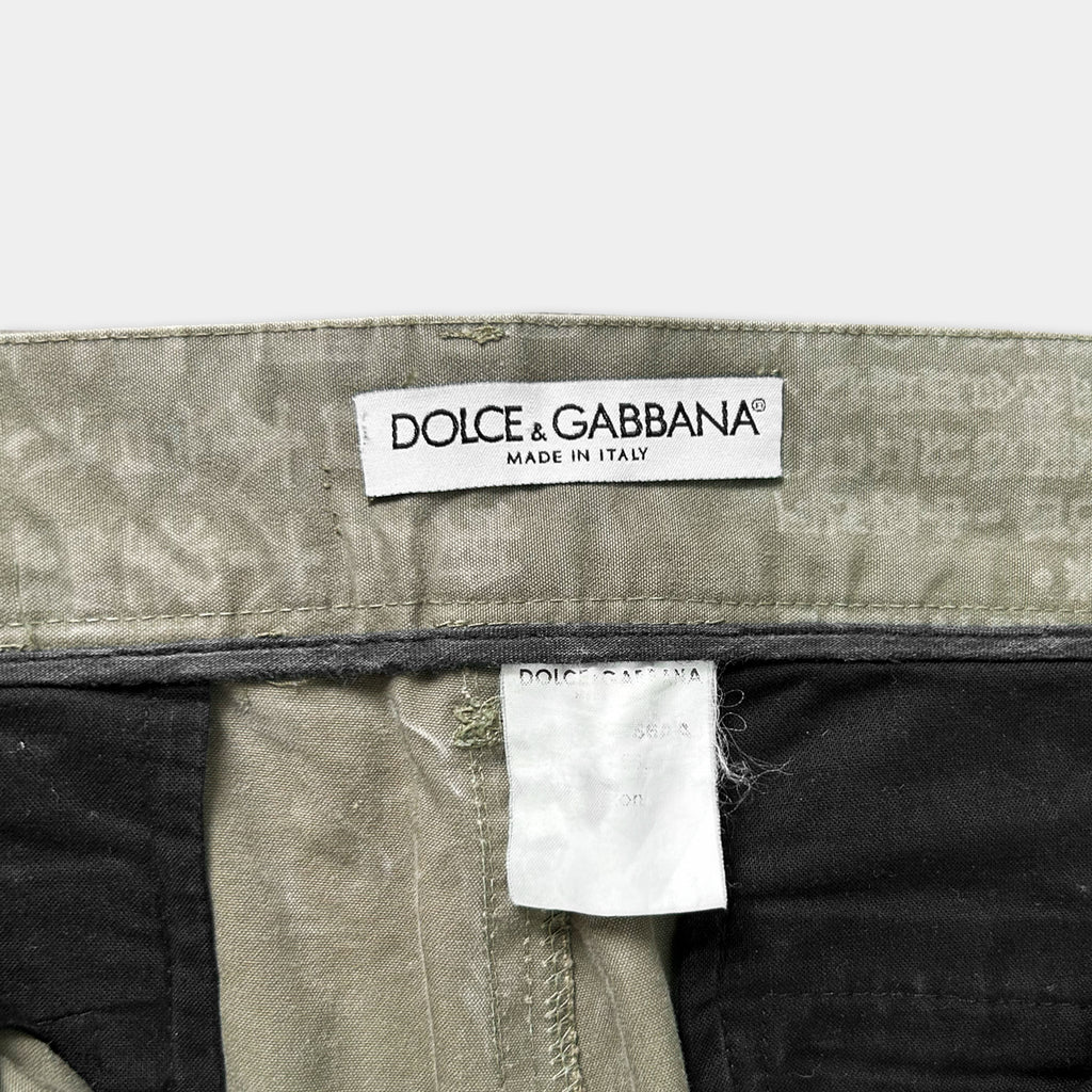 a close-up view of a label on a pair of olive green trousers, with the brand name "DOLCE & GABBANA" printed on it.