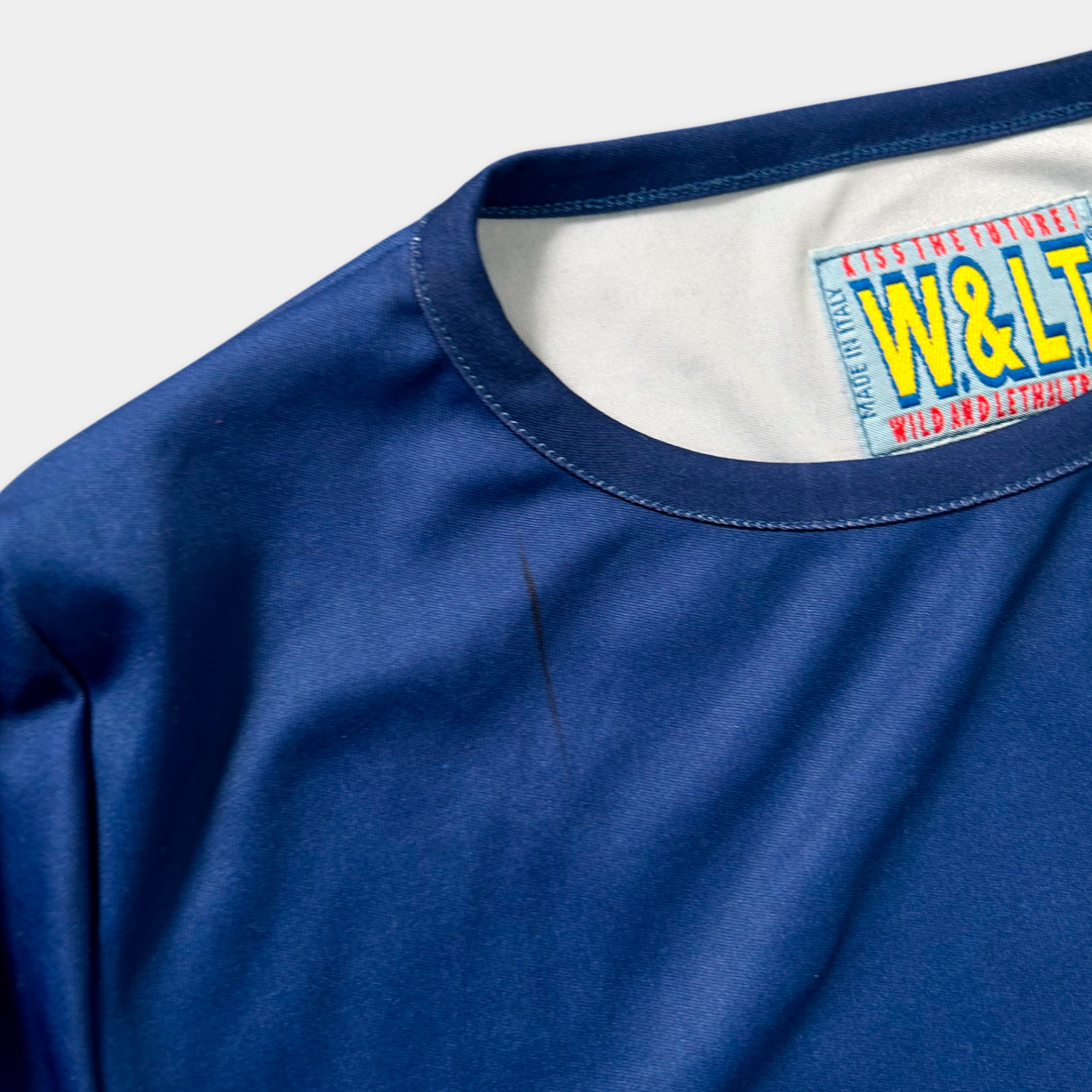 A close-up view of a blue t-shirt with a label on the collar.