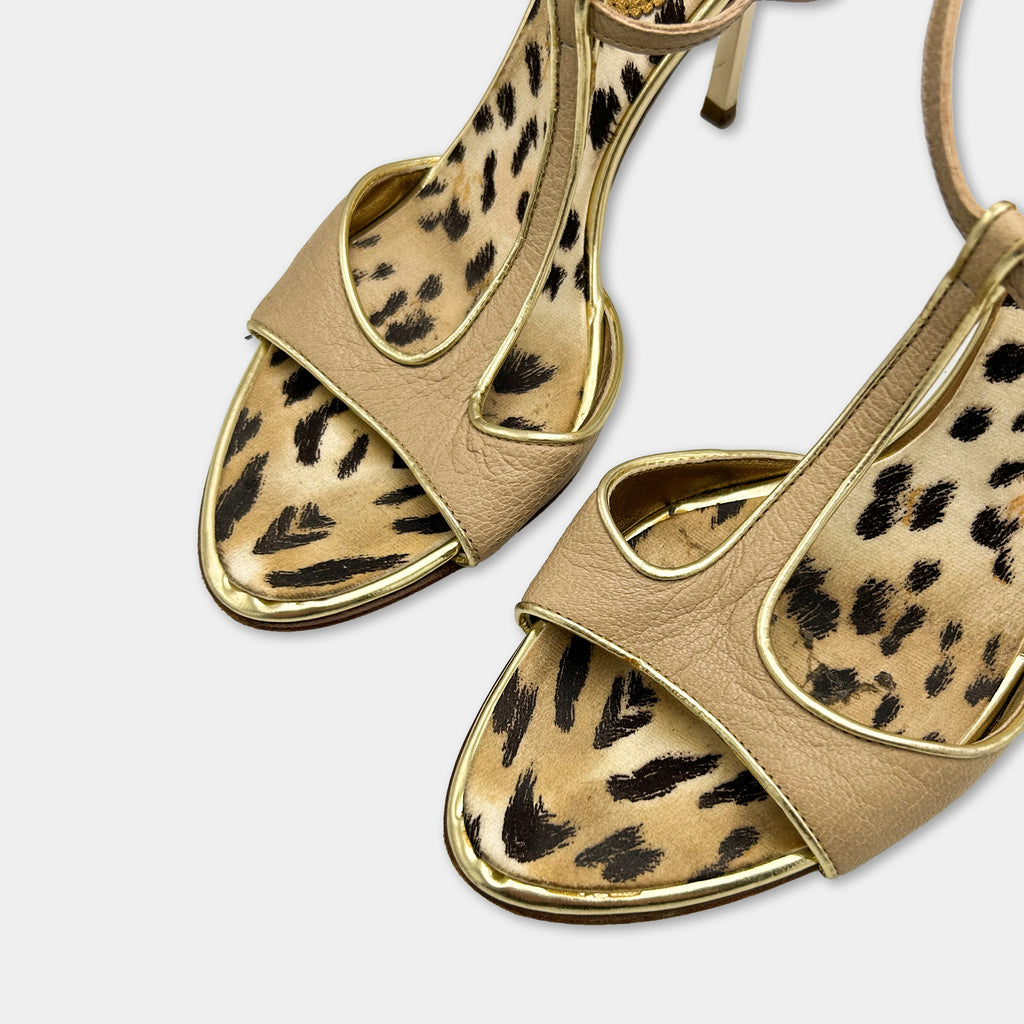 A pair of tan high-heeled sandals with leopard print patterns on the upper part.