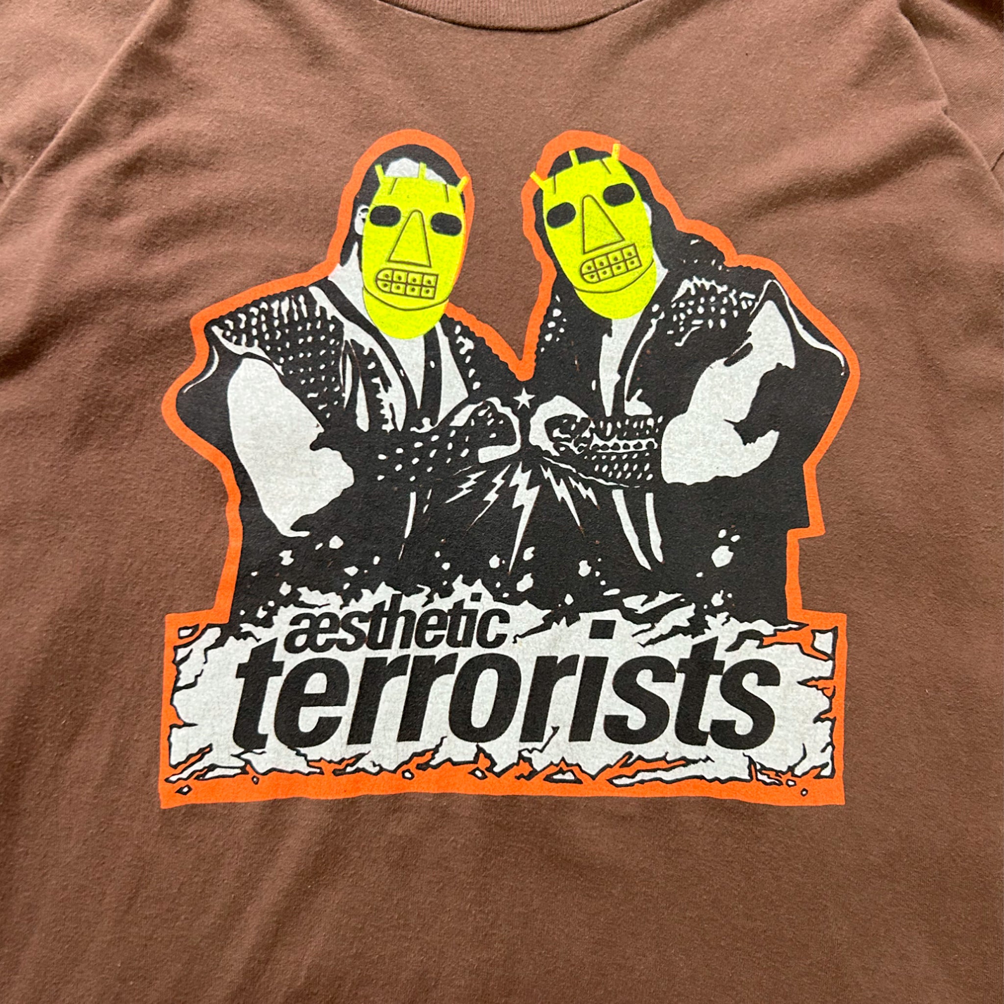 two people wearing yellow masks with the text "Aesthetic Terrorists" below them.