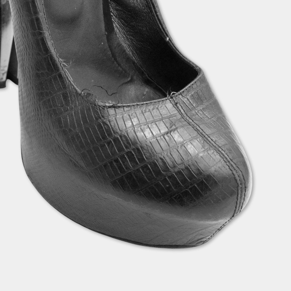 A close-up black and white image of a high-heeled shoe with a distinctive design.