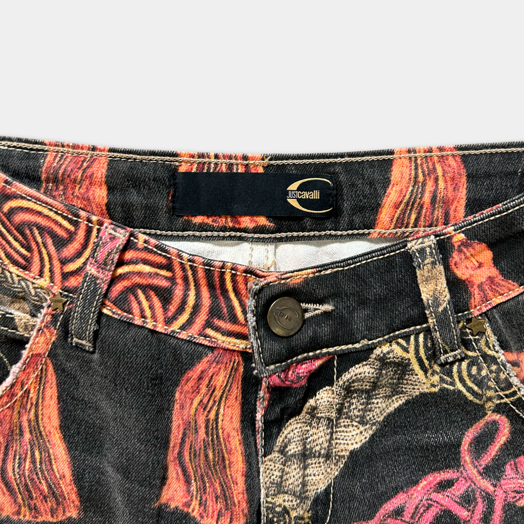 A close-up view of a pair of colorful, patterned jeans with a label on the waistband.