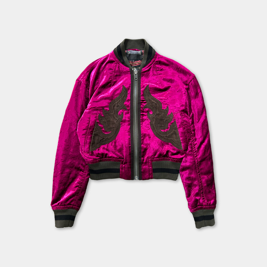 A bright pink velvet jacket with black floral embroidery on the front.