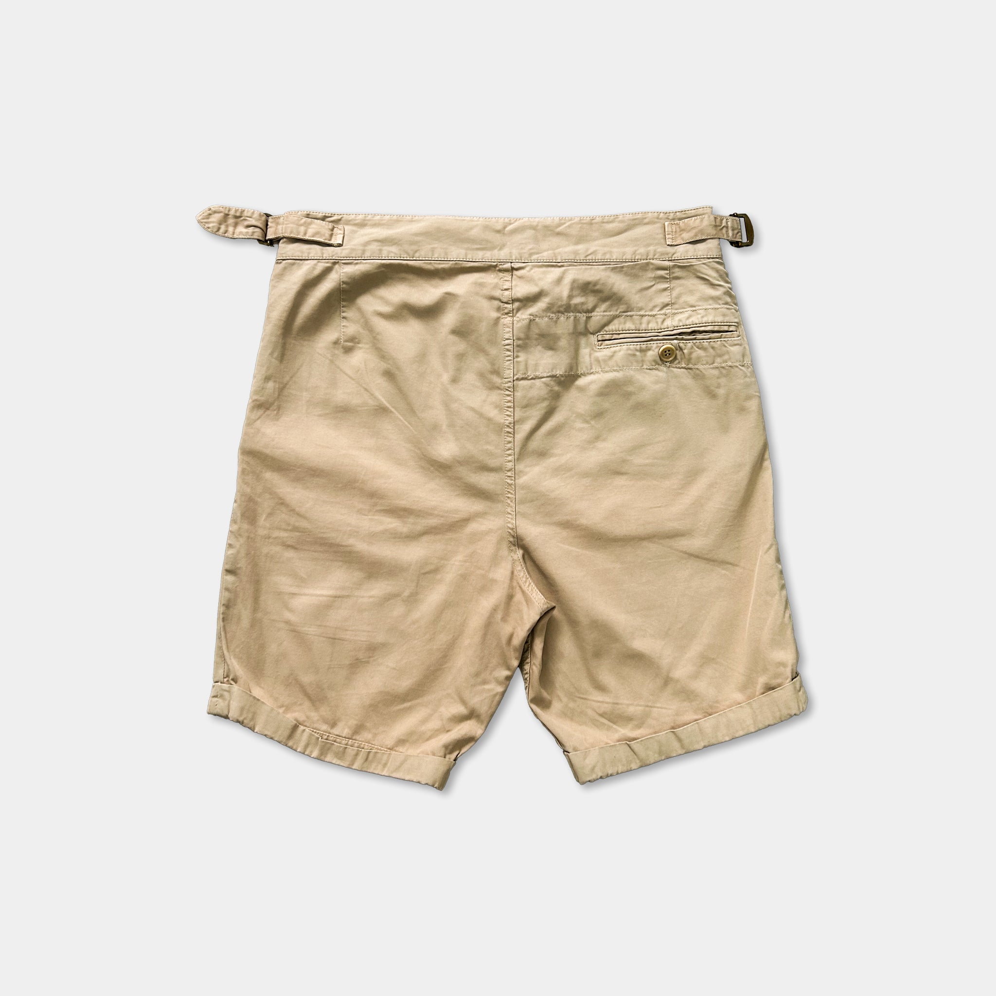 A pair of khaki cargo shorts with a belt and pocket.
