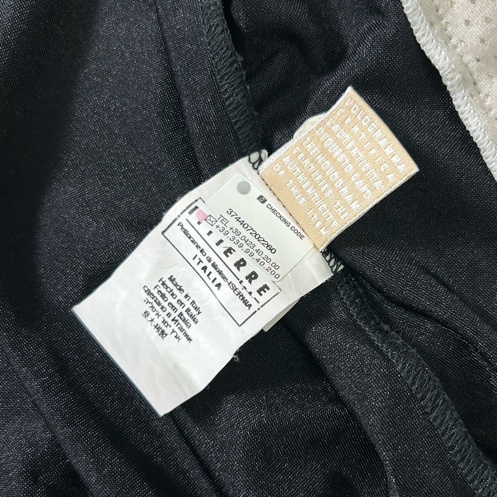 a close-up view of a black fabric, possibly a piece of clothing, with a white label attached to it. The label appears to contain text and possibly a barcode or identification code.