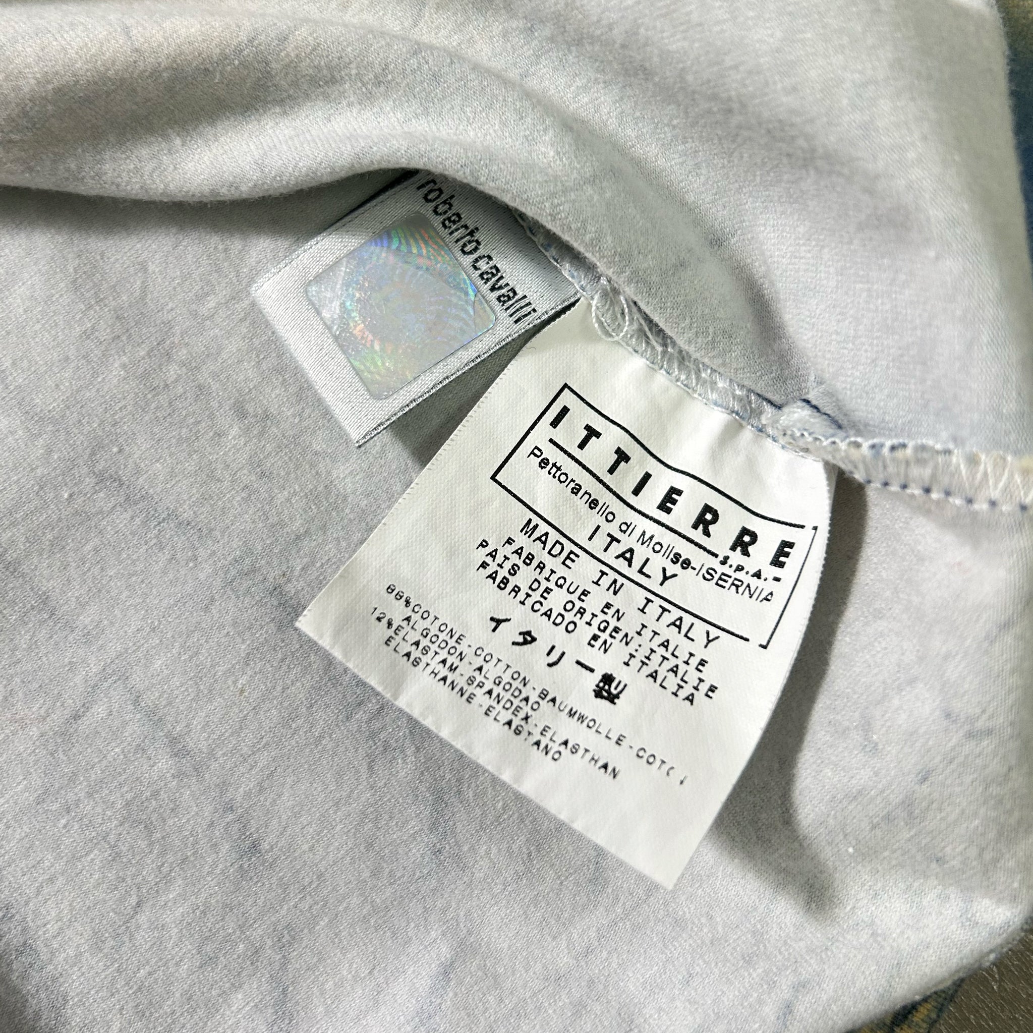 a close-up view of a white fabric, possibly a garment or textile, with a label attached to it. The label appears to be a product label or tag, providing information about the item.