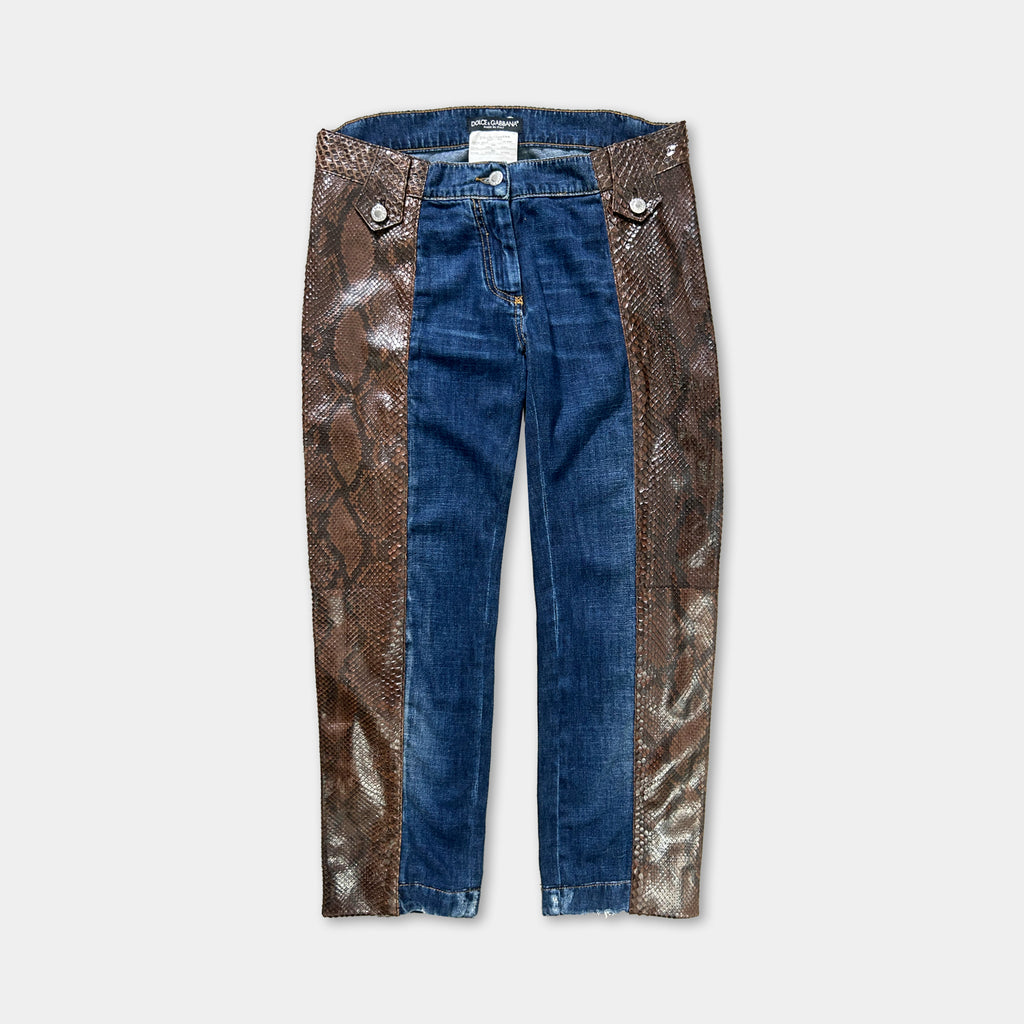 A pair of blue jeans with a brown snake skin-like pattern on the left leg.