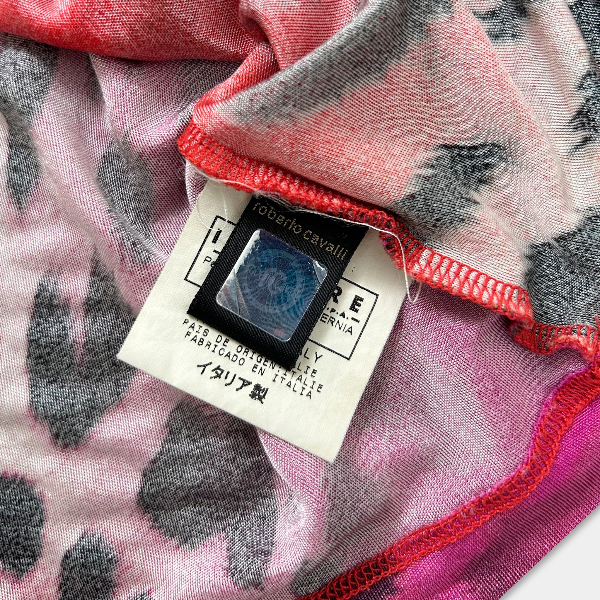 a close-up view of a fabric with a label attached to it, featuring text and a small circular logo.