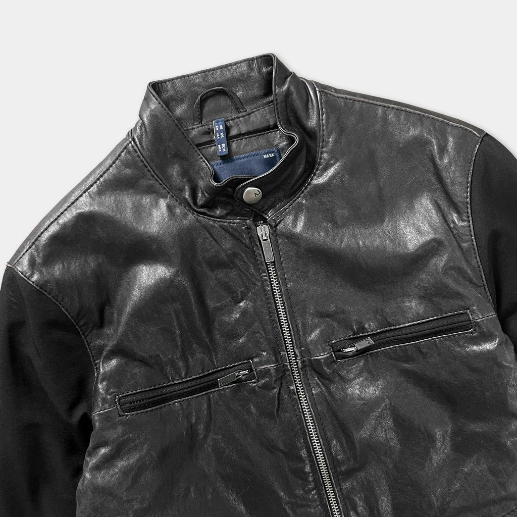 A close-up view of a black leather jacket with a zipper and two pockets.