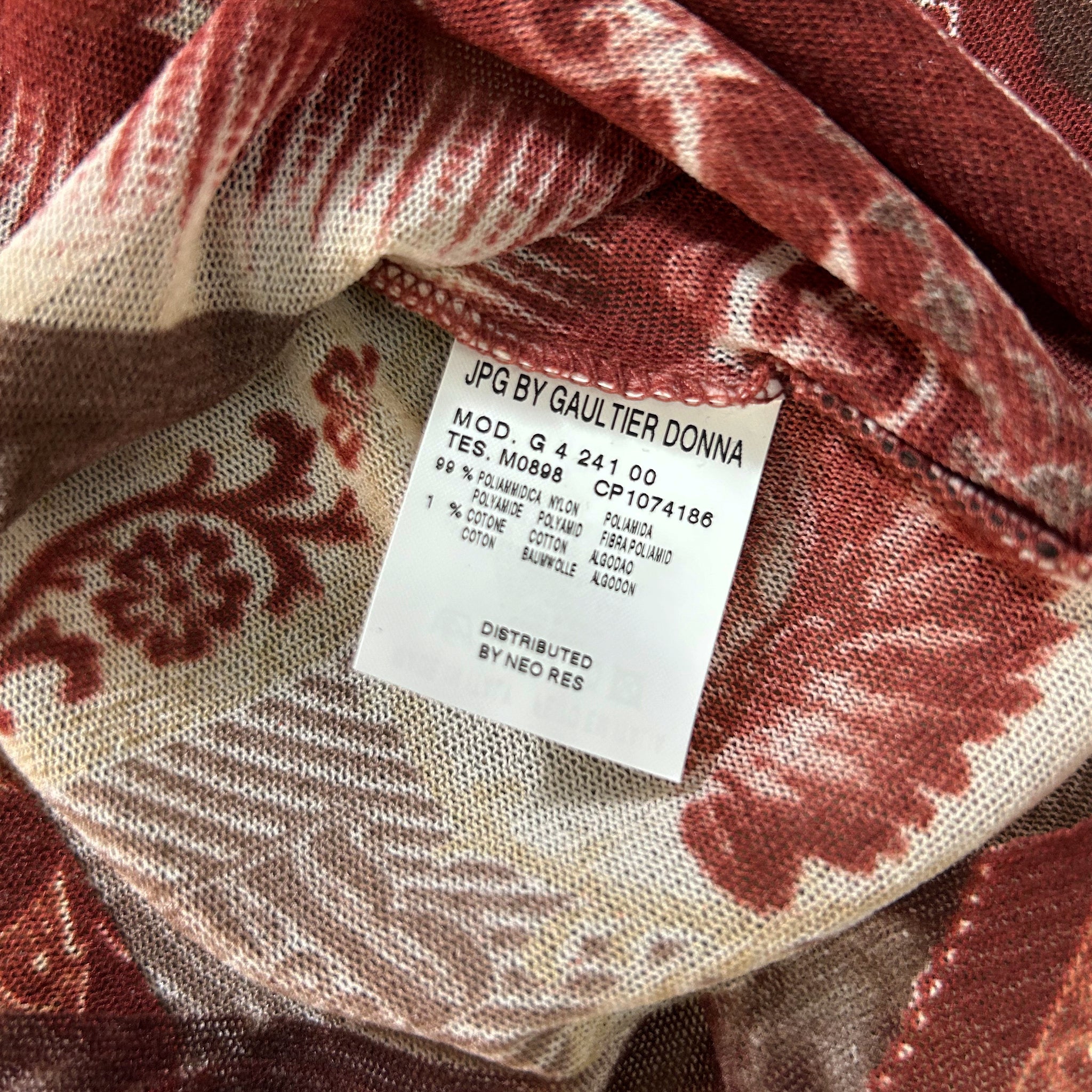 a close-up view of a fabric label with text and numbers, placed on a fabric with a floral pattern.