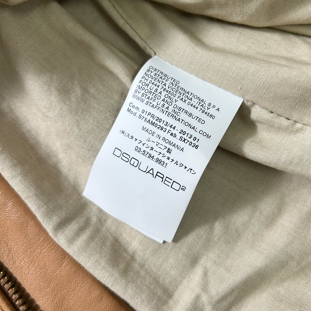 a close-up view of a label on a piece of clothing, likely a jacket or coat, with a beige fabric background.
