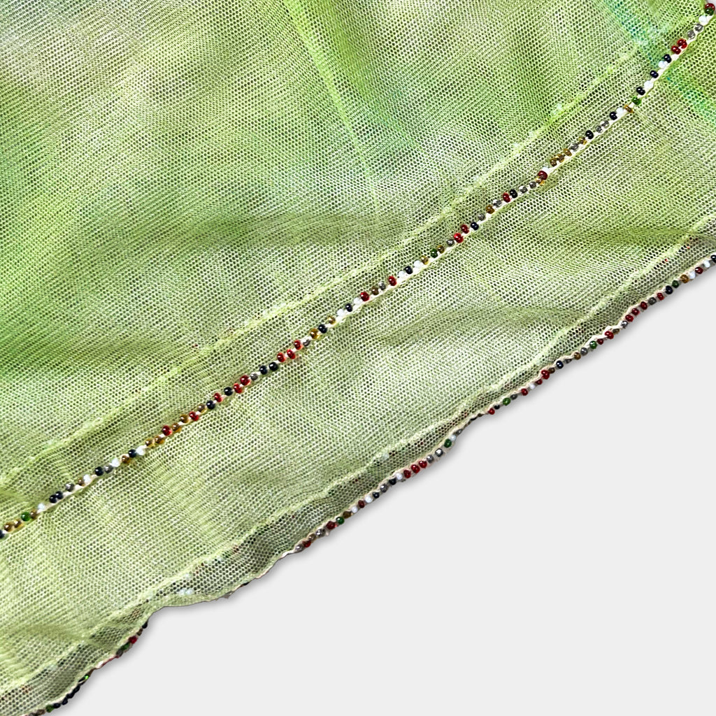a close-up view of a green fabric with a decorative beaded trim.