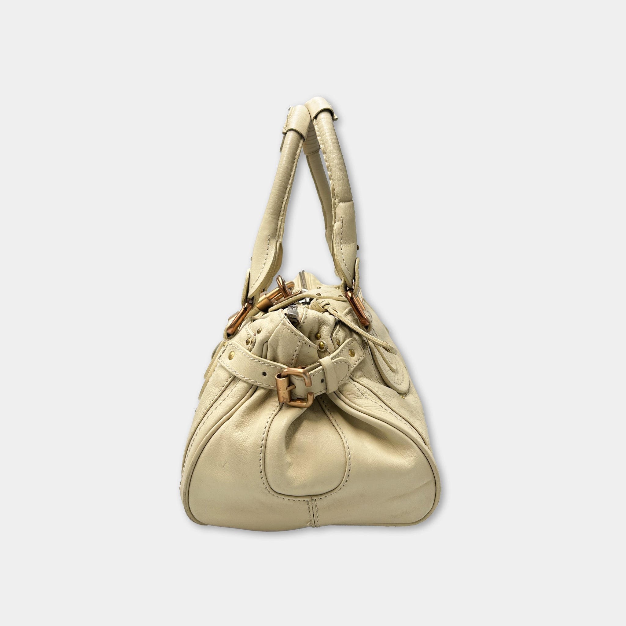 A tan leather handbag with a curved shape and two handles, one on each side.