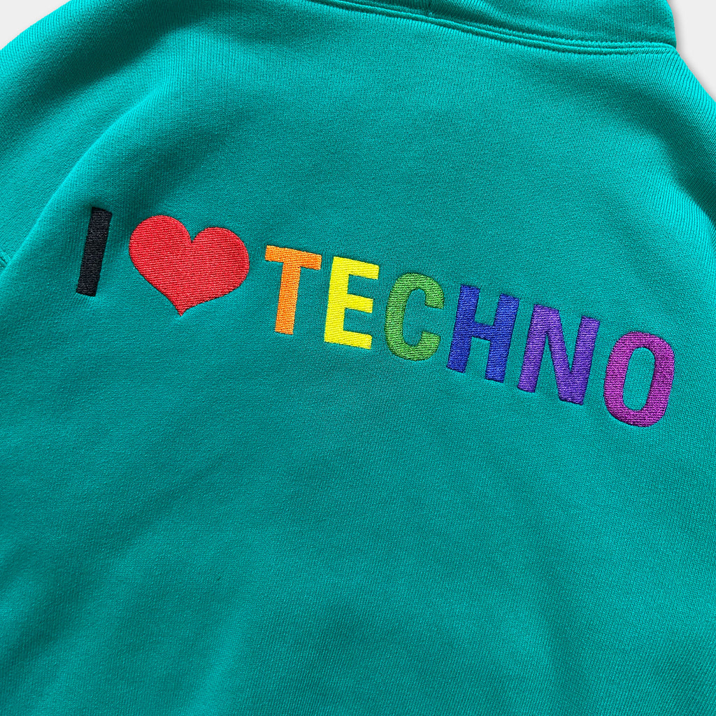 A close-up of a teal-colored hoodie with the text "I ♥ TECHNO" embroidered on it.