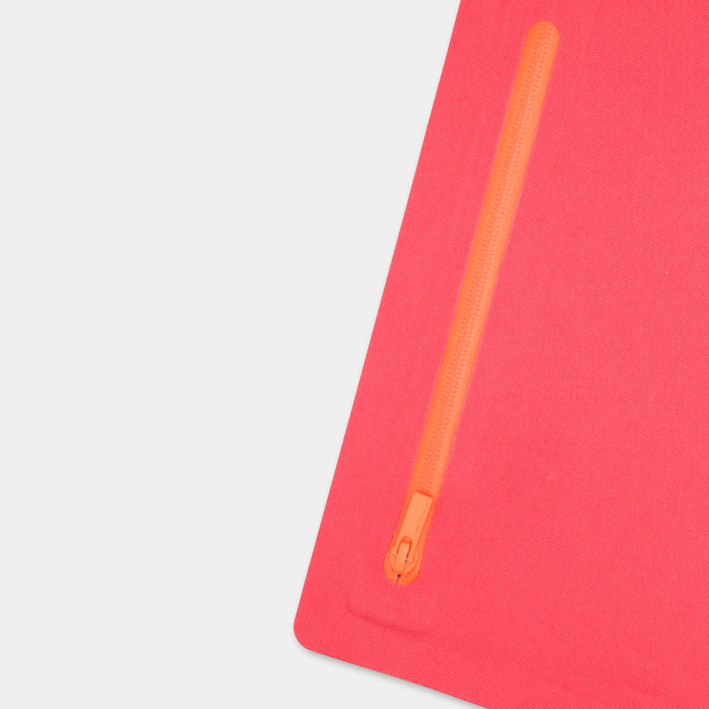 a red object with an orange zipper on it, placed on a white surface.