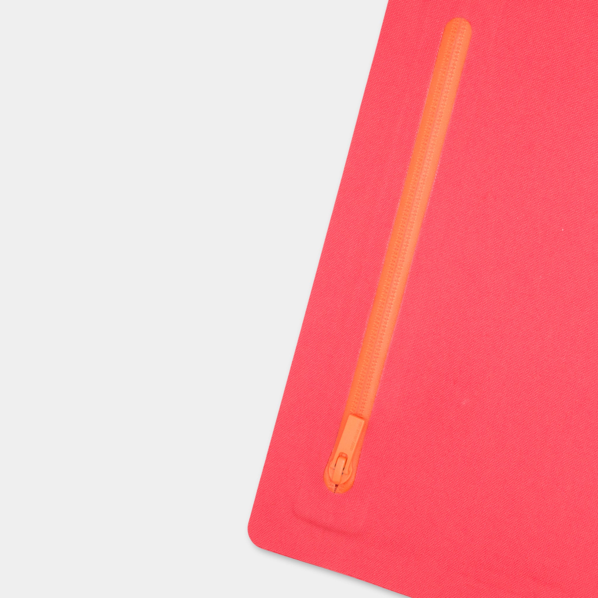 a red object with an orange zipper on it, placed on a white surface.