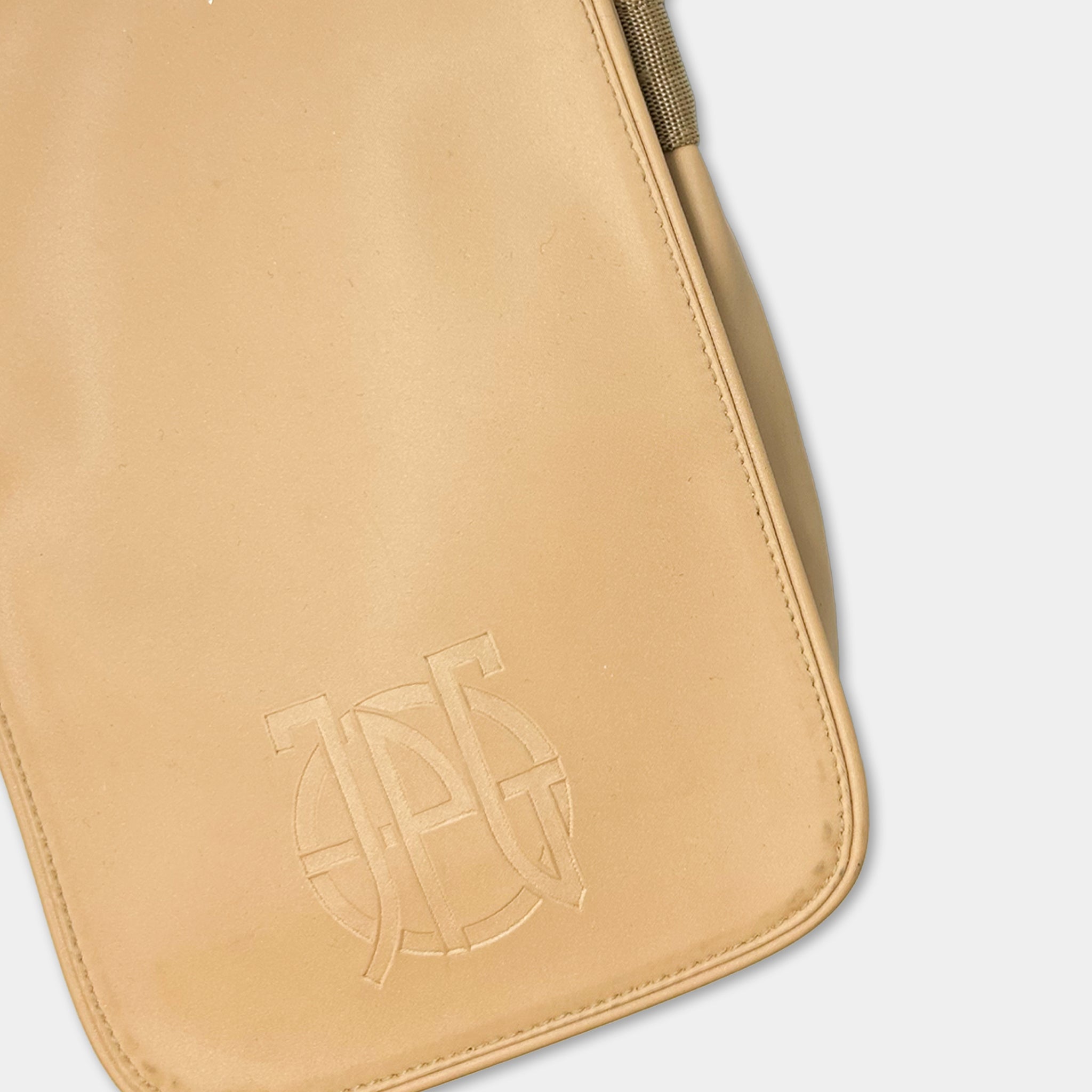 A tan-colored leather bag with a logo embossed on it.