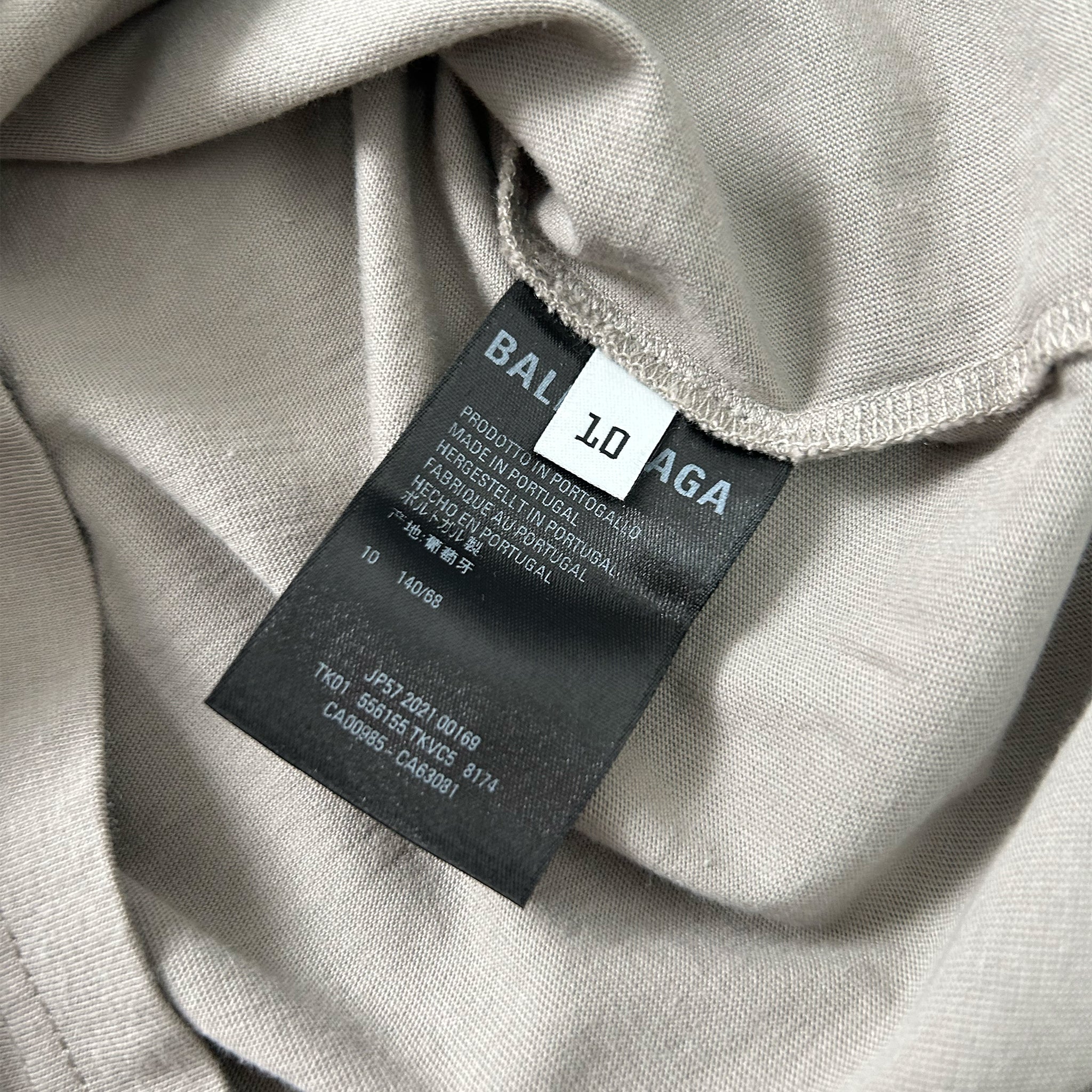 A close-up view of a grey fabric with a black label attached to it, displaying text and numbers.