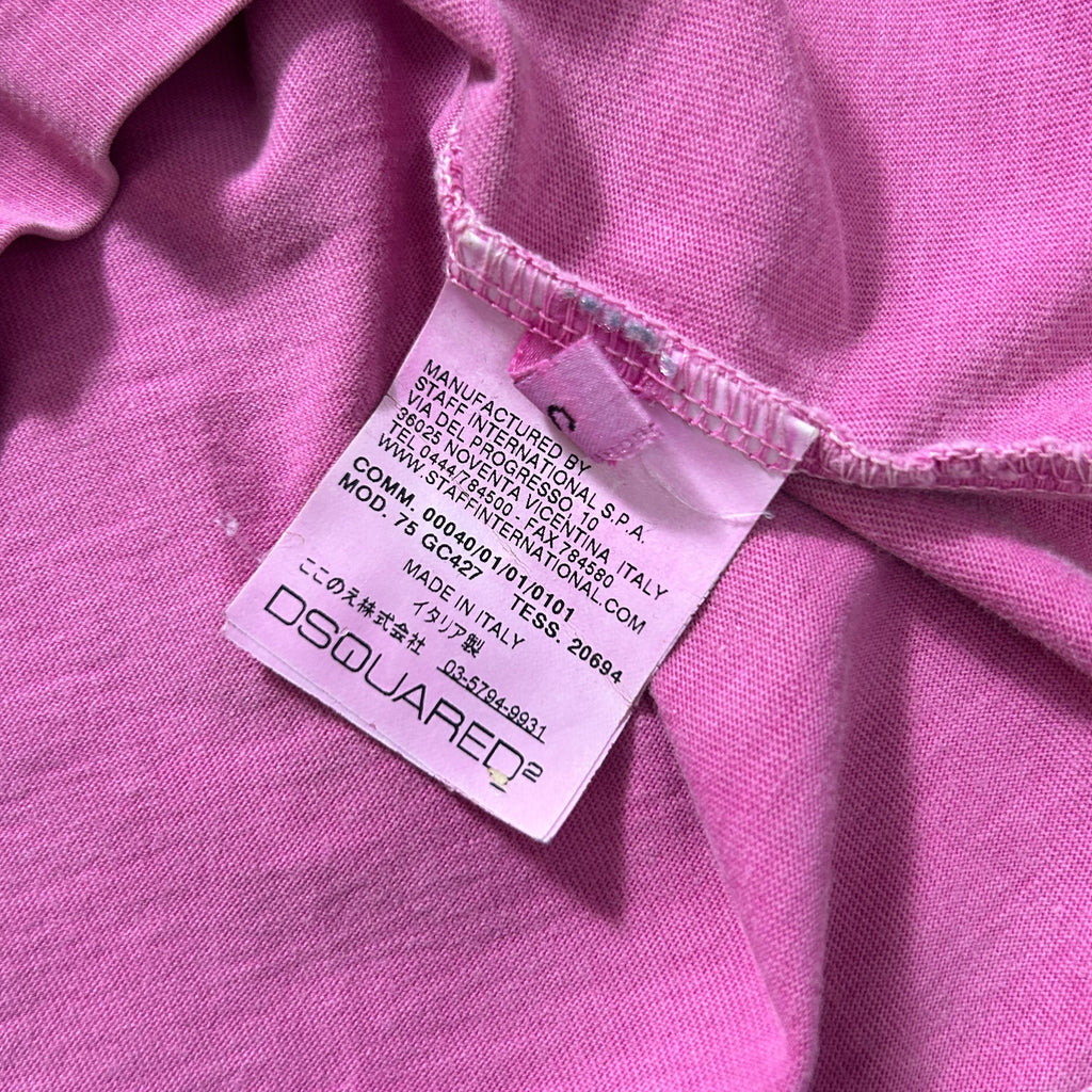 A close-up image of a pink fabric with a label attached to it, which appears to be a tag or label from a clothing item.