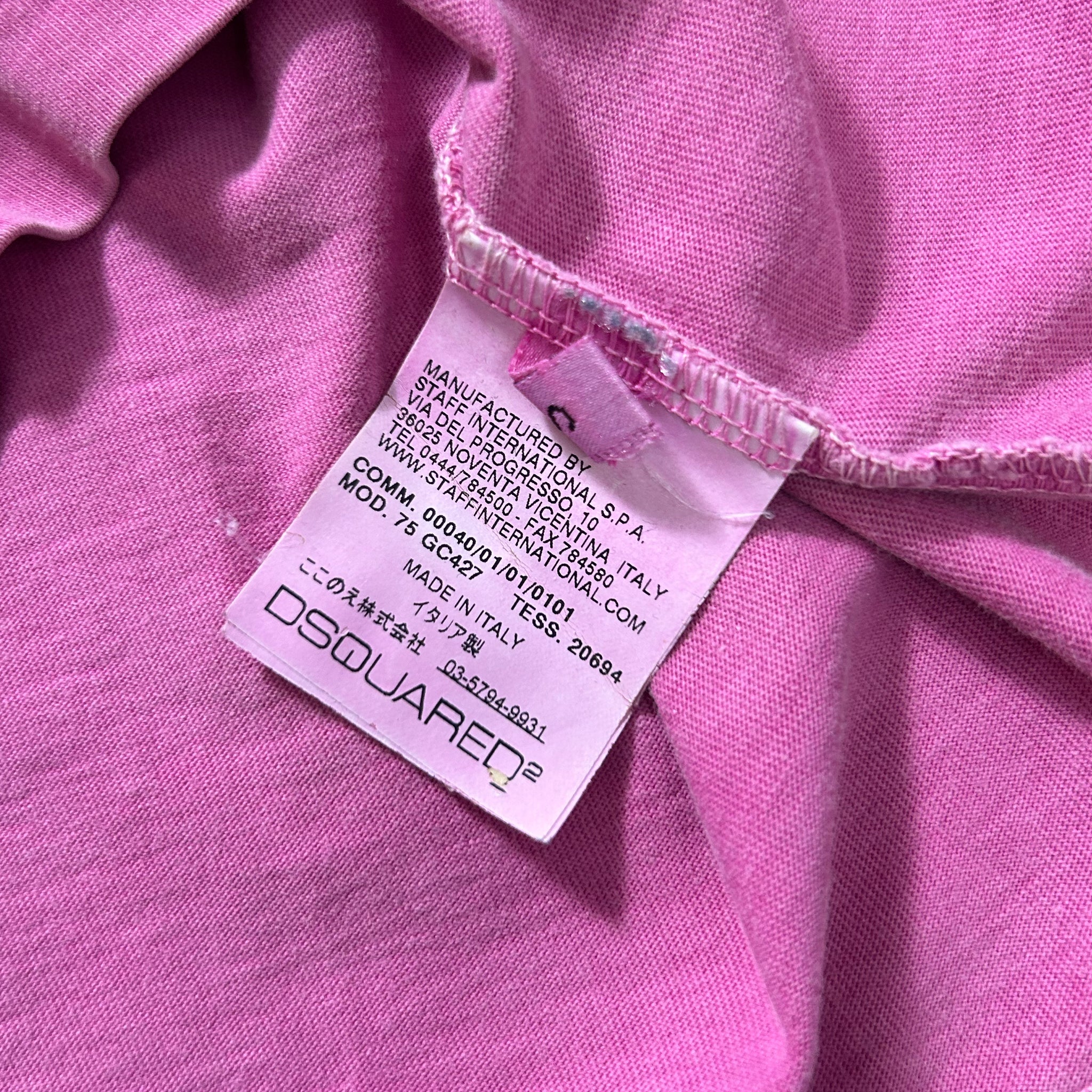 A close-up image of a pink fabric with a label attached to it, which appears to be a tag or label from a clothing item.