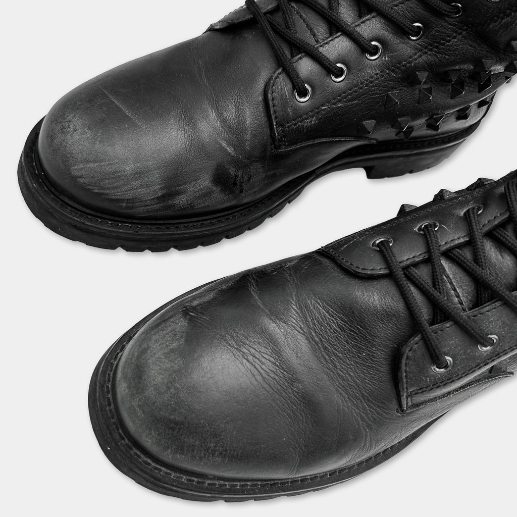 A close-up view of a pair of black leather boots with laces and soles.