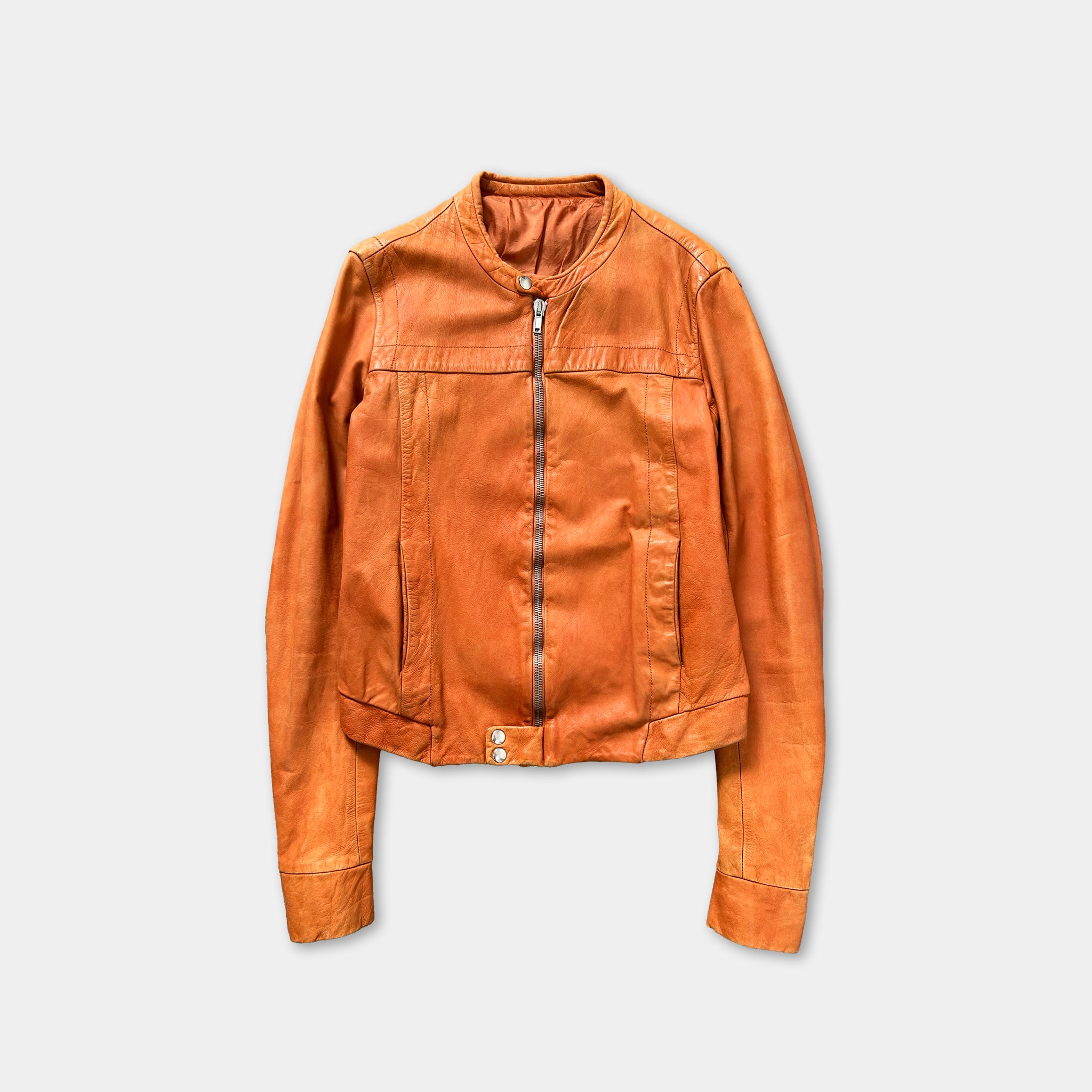 A single orange leather jacket with a zipper and pockets, displayed against a plain white background.