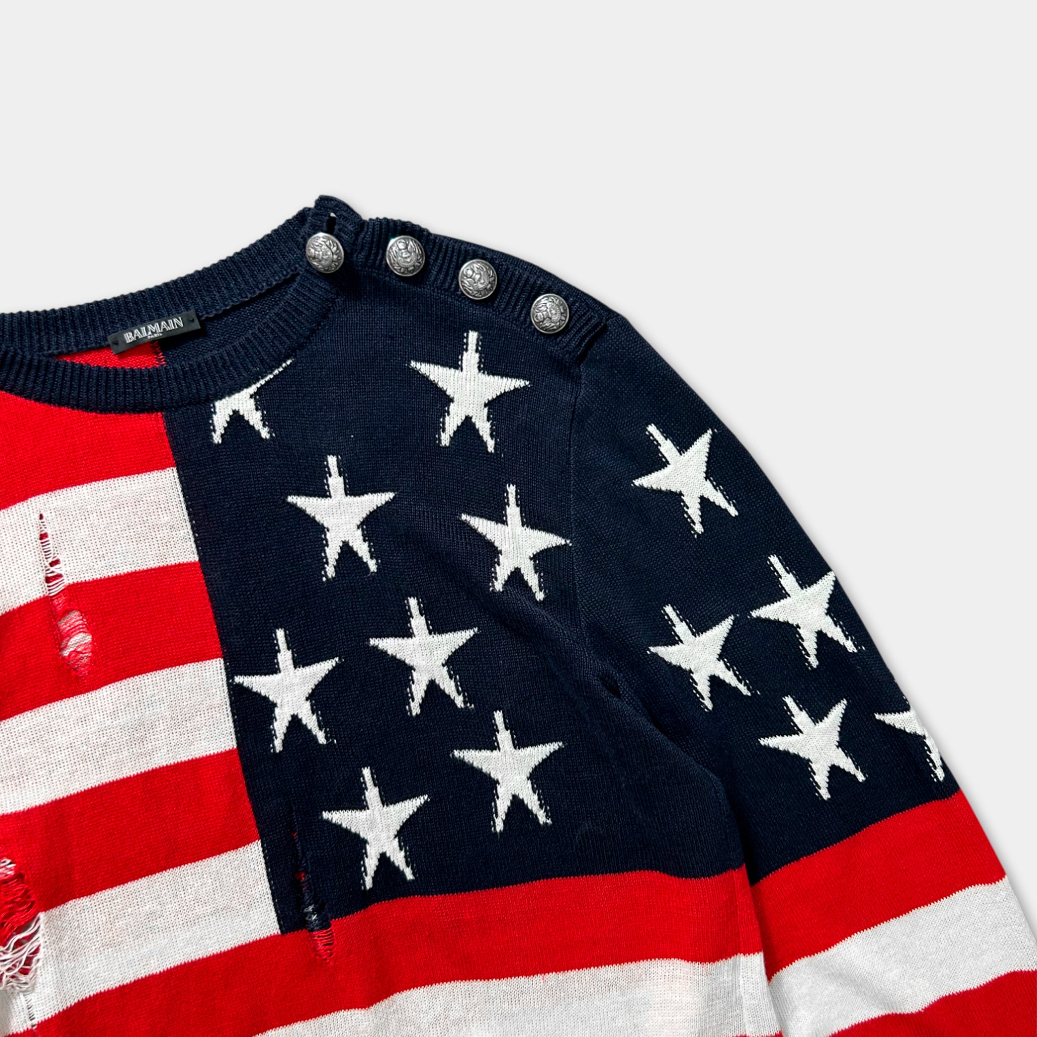 A close-up view of a sweater with a red, white, and blue striped pattern, featuring a prominent American flag design.