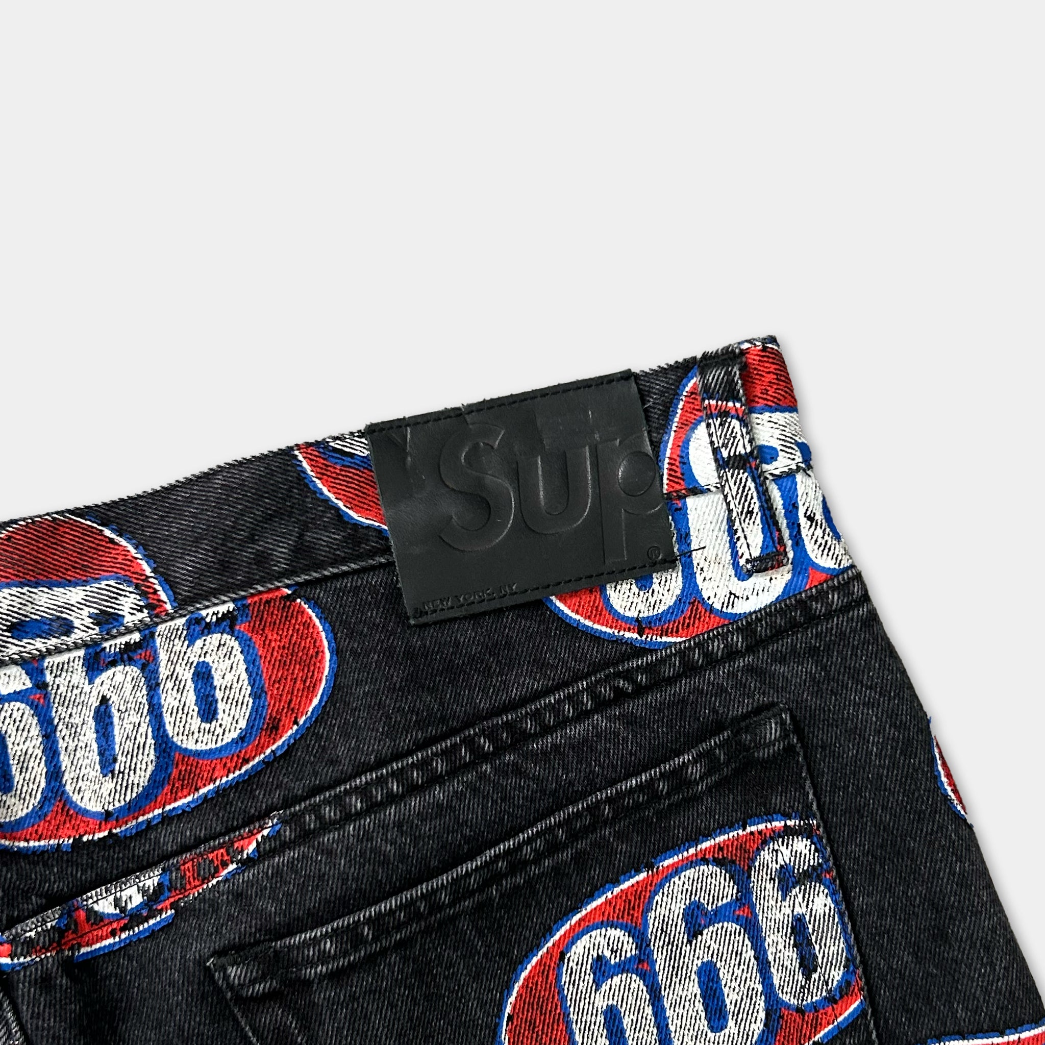 a pair of black jeans with a prominent red and blue logo on the back pocket.