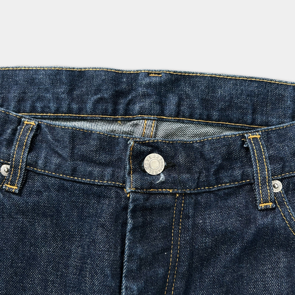 A close-up view of a pair of blue jeans, focusing on the waistband and zipper.