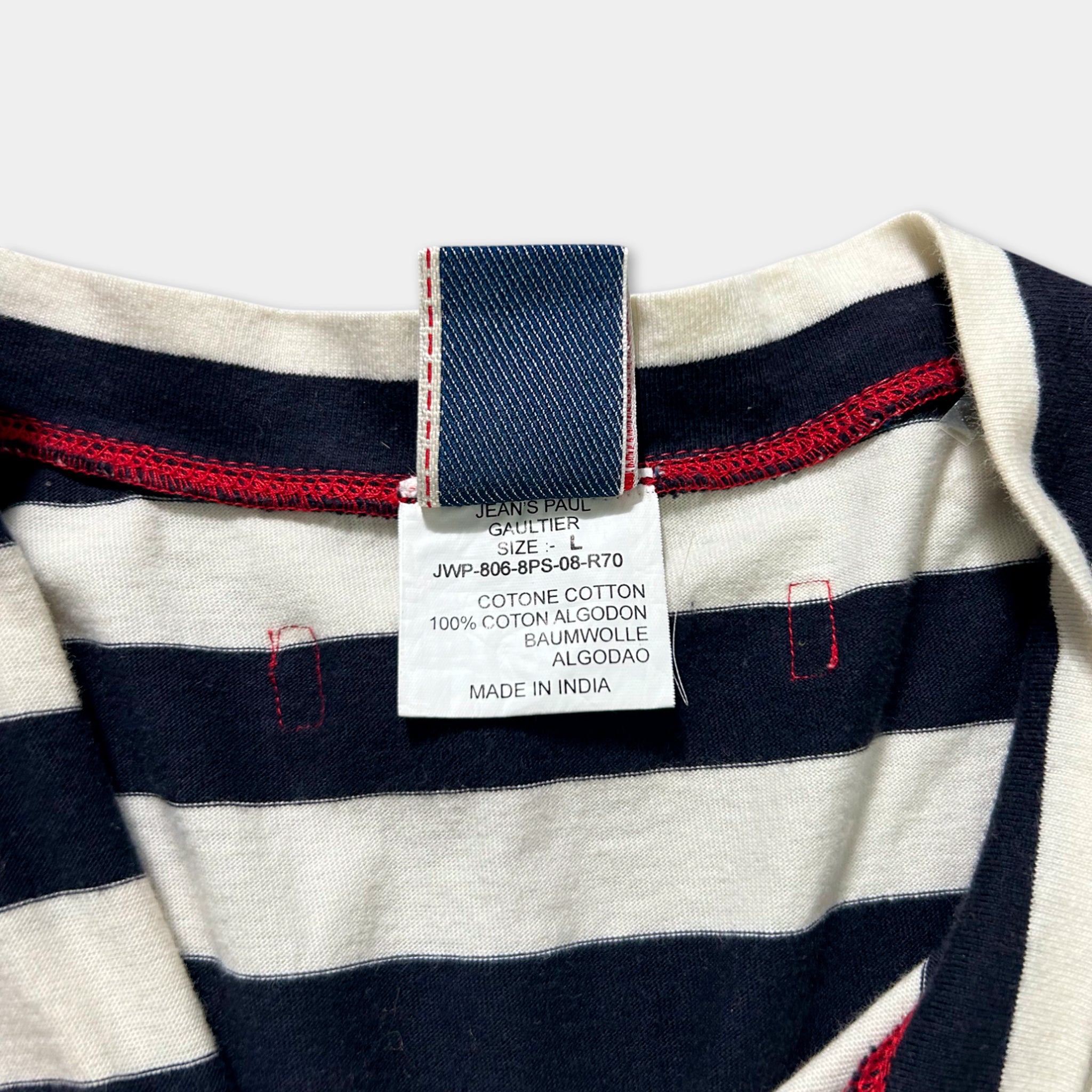 a close-up view of a clothing label attached to a striped shirt, with a red and blue tag.