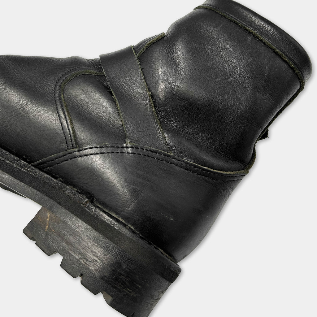 A close-up view of a black leather boot, showing the sole, heel, and part of the upper part.