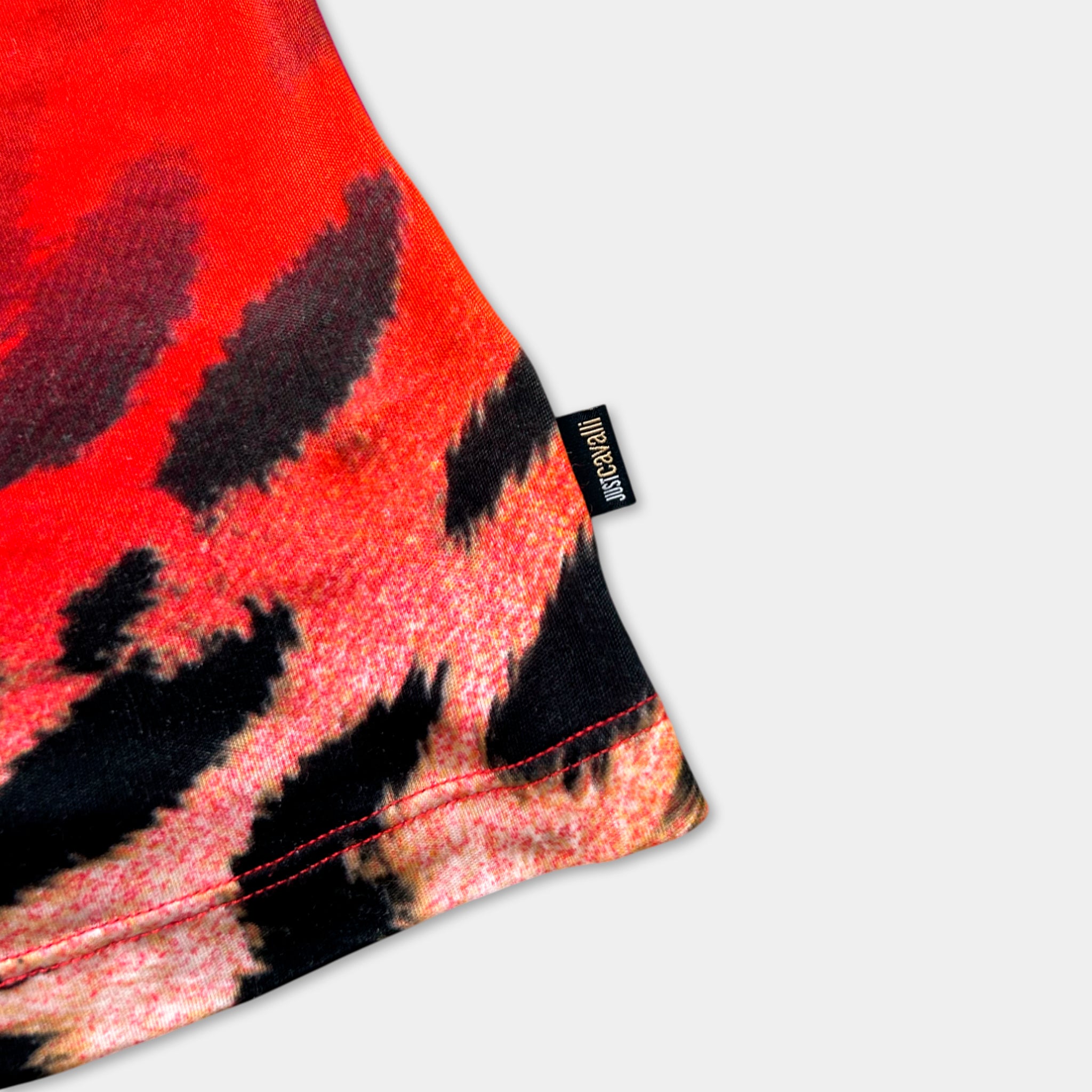 a close-up view of a red and black patterned fabric, with a small black label attached to the edge of the fabric.
