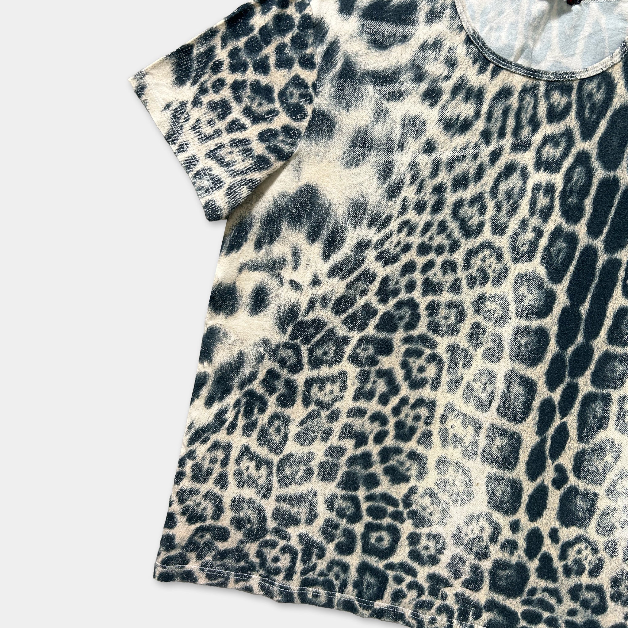 A t-shirt with a leopard print pattern, featuring a mix of black and white spots.