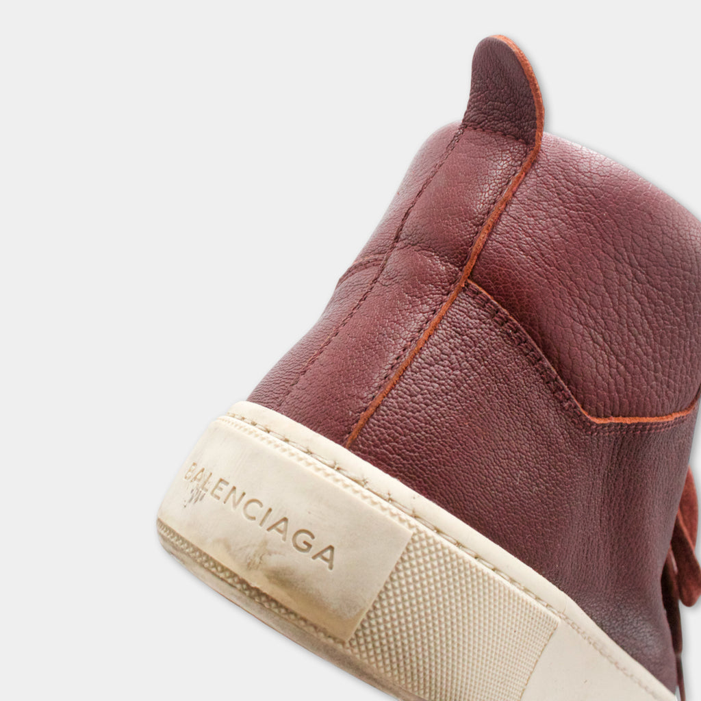 A close-up view of a brown leather sneaker with a white sole, featuring the Balenciaga logo on the side.