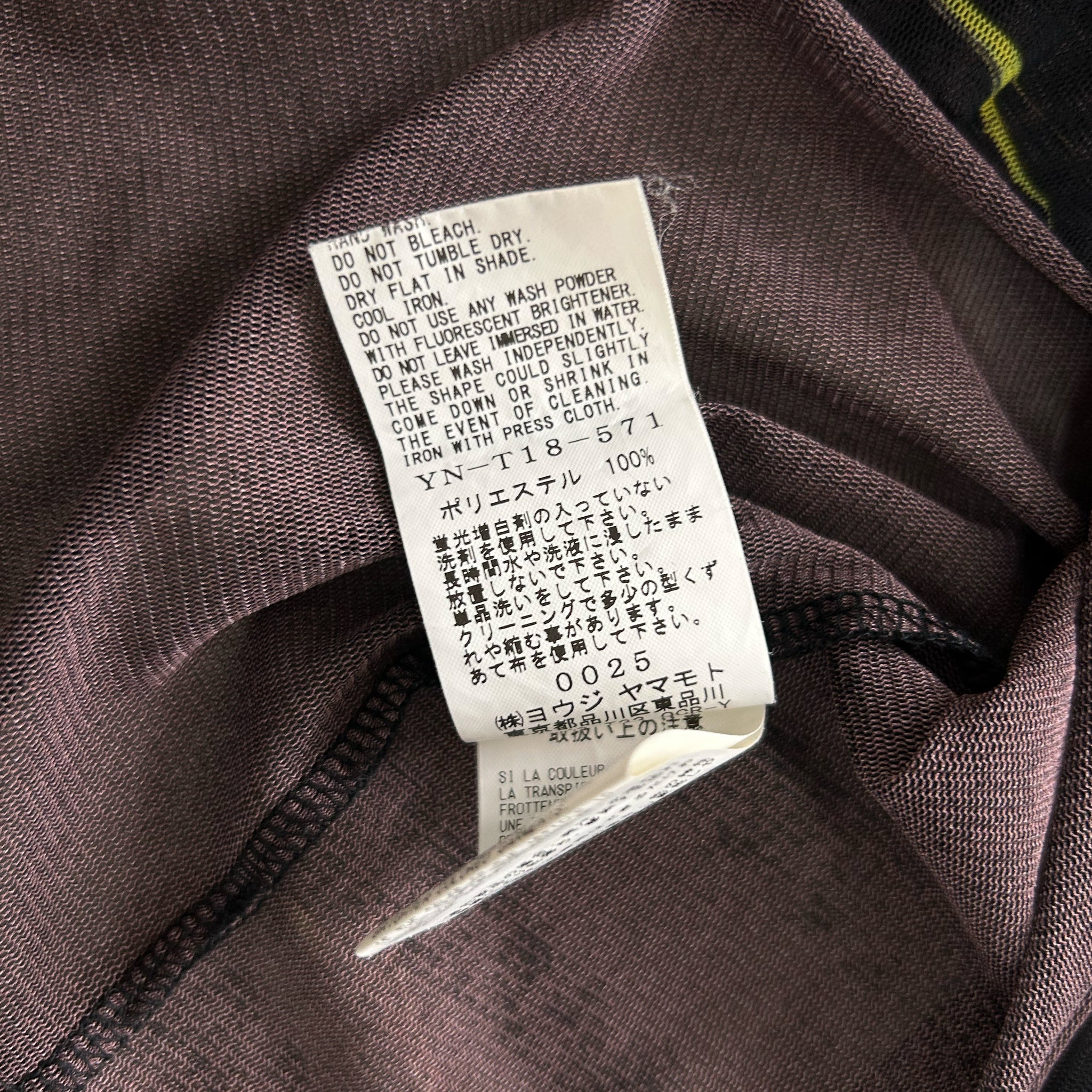 a close-up view of a fabric label with text in Japanese, attached to a garment.
