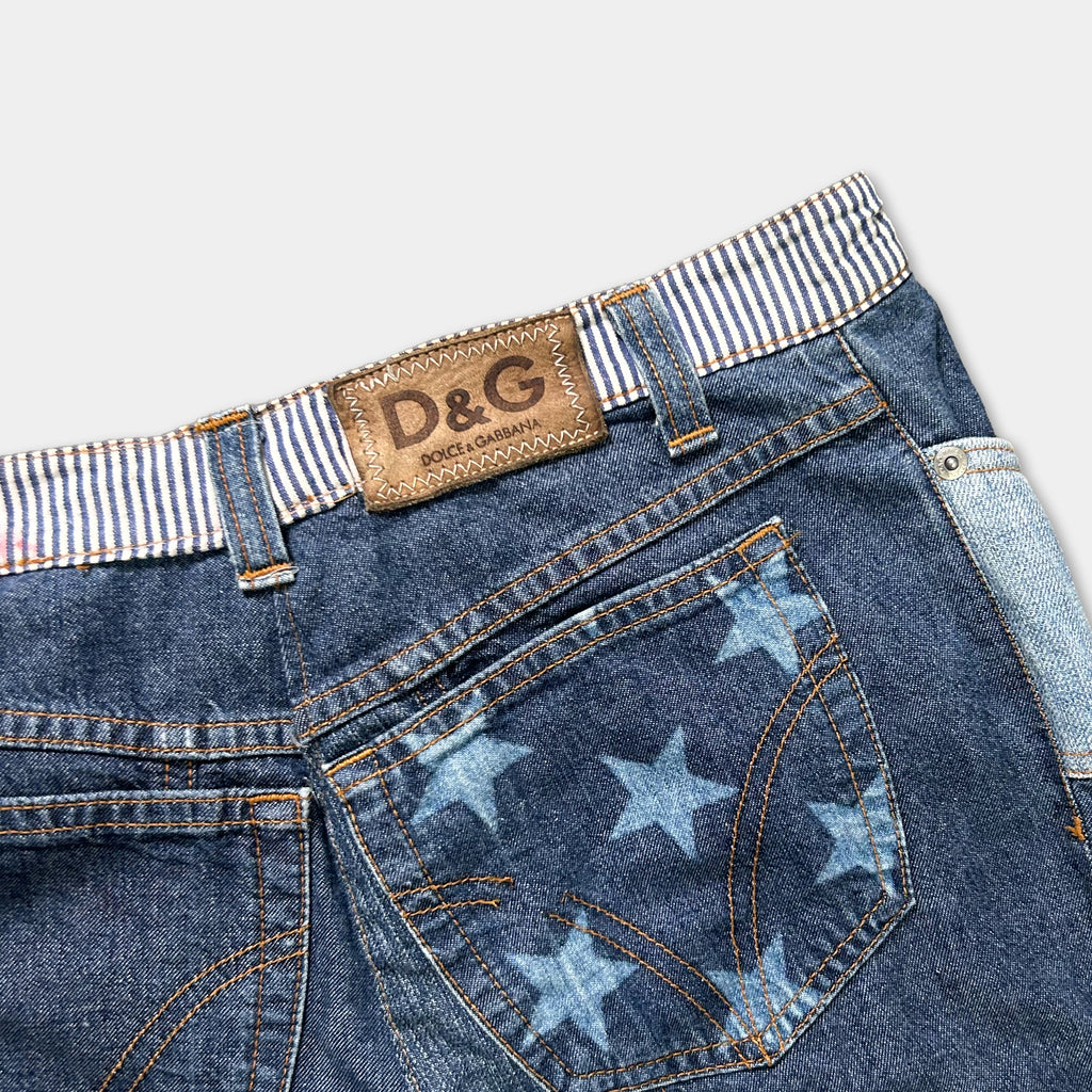 A close-up view of a pair of blue denim jeans with a star-patterned pocket and a brown leather belt buckle.