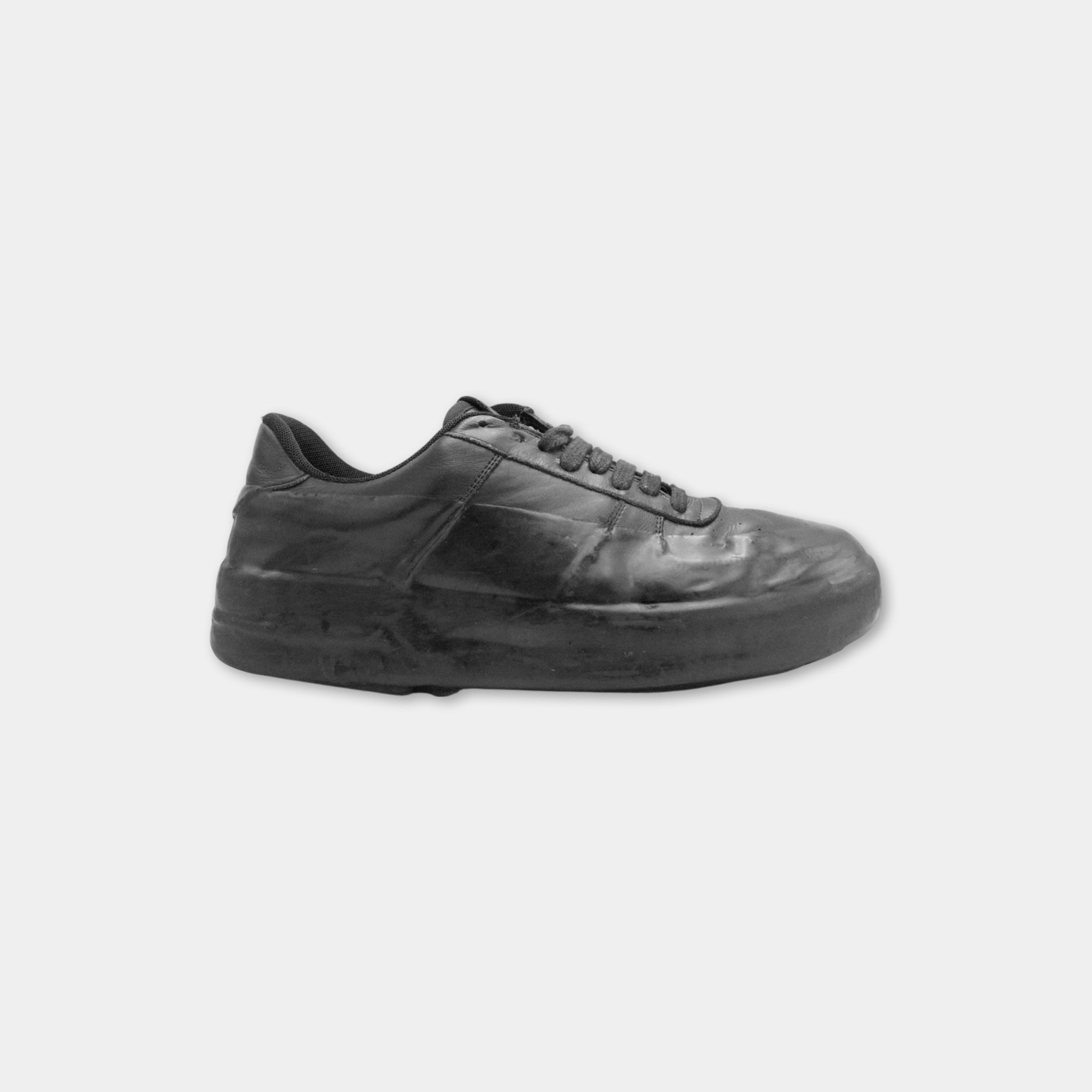 A worn black sneaker with visible signs of use and wear.