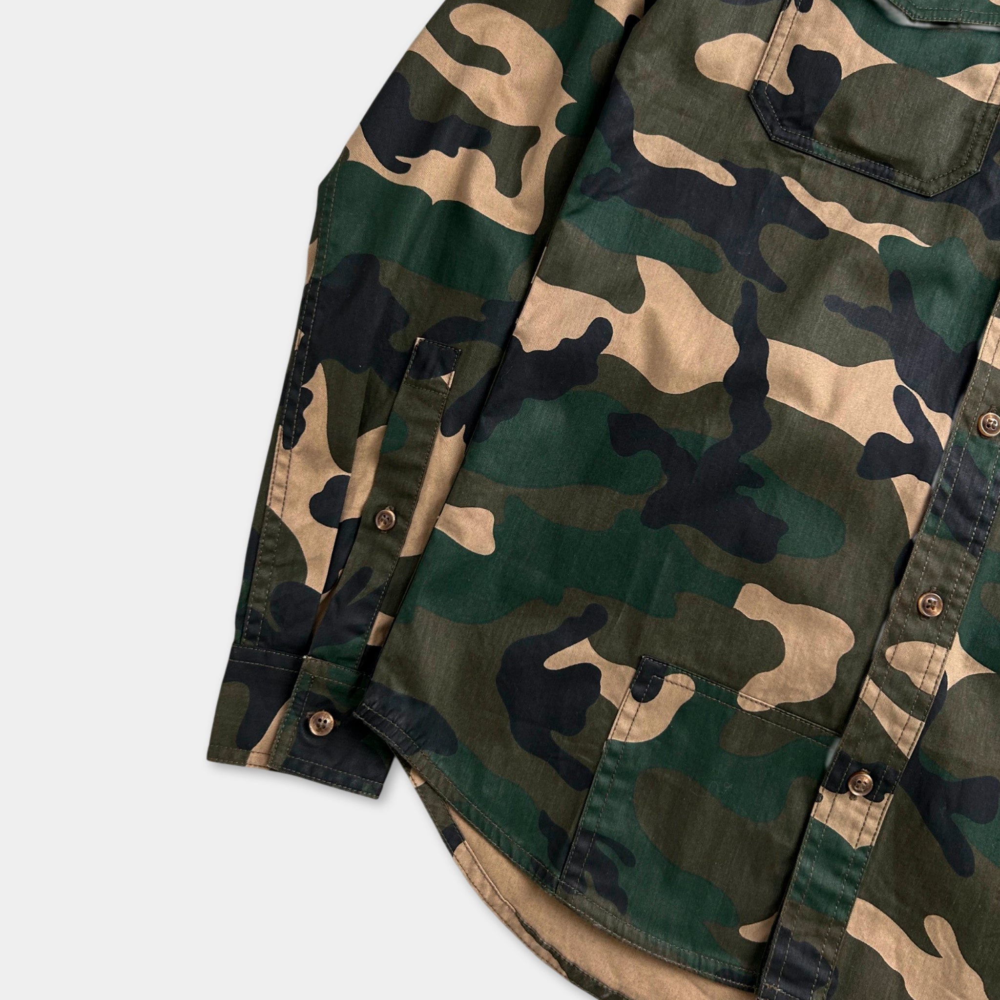 A camouflage-patterned shirt with a button-down front and sleeves, displayed on a white background.