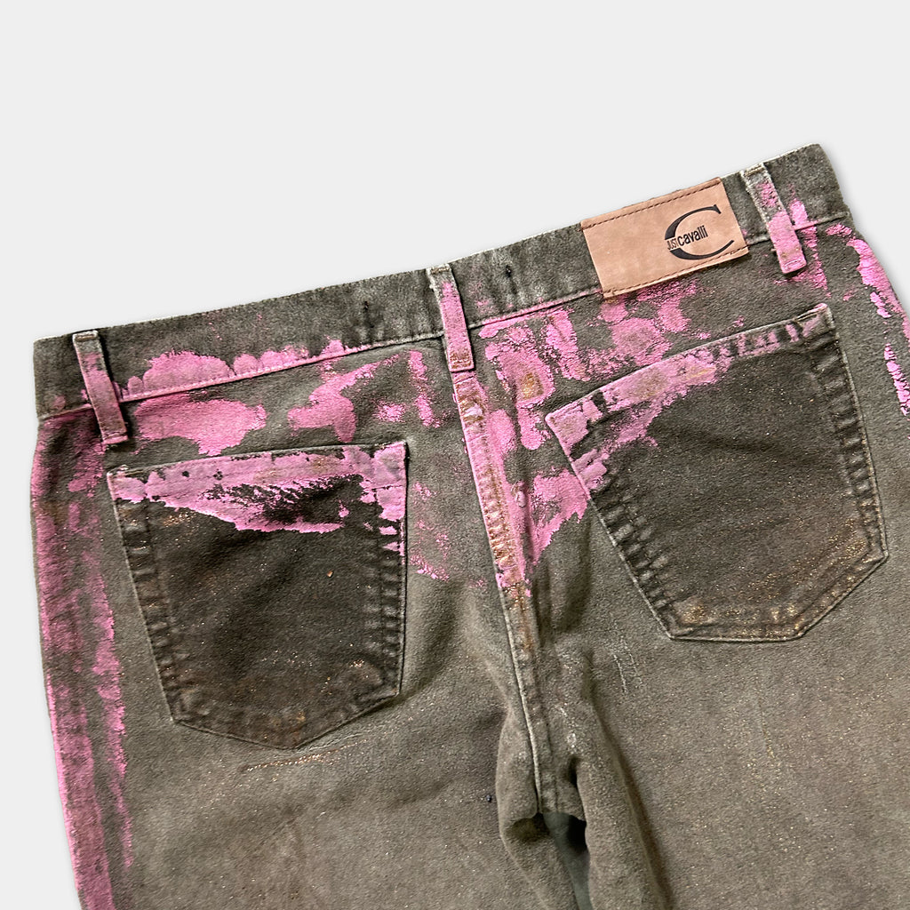 a pair of distressed jeans with pink splatters on the back pocket and the waistband.