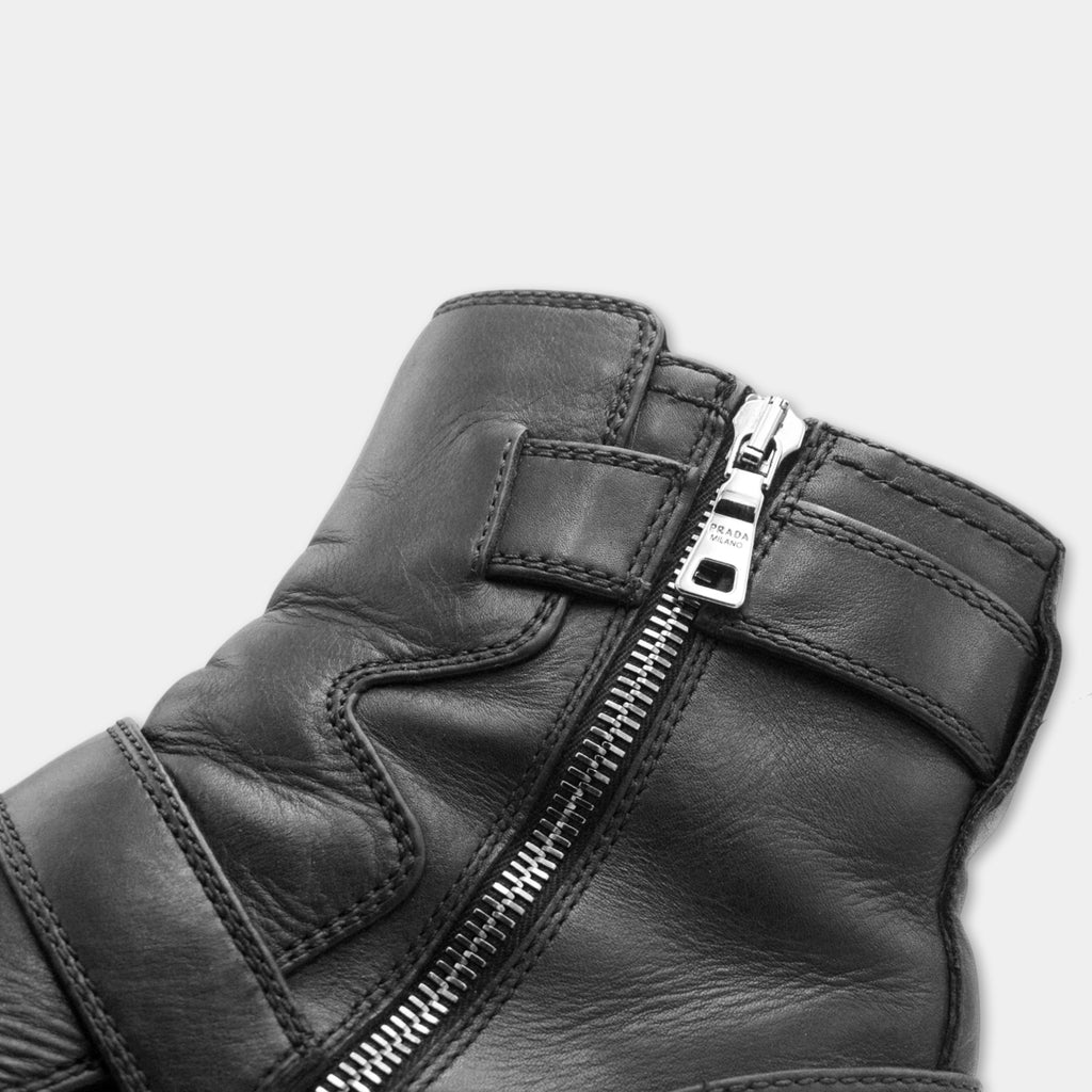 A close-up view of a black leather boot with a zipper and buckles.