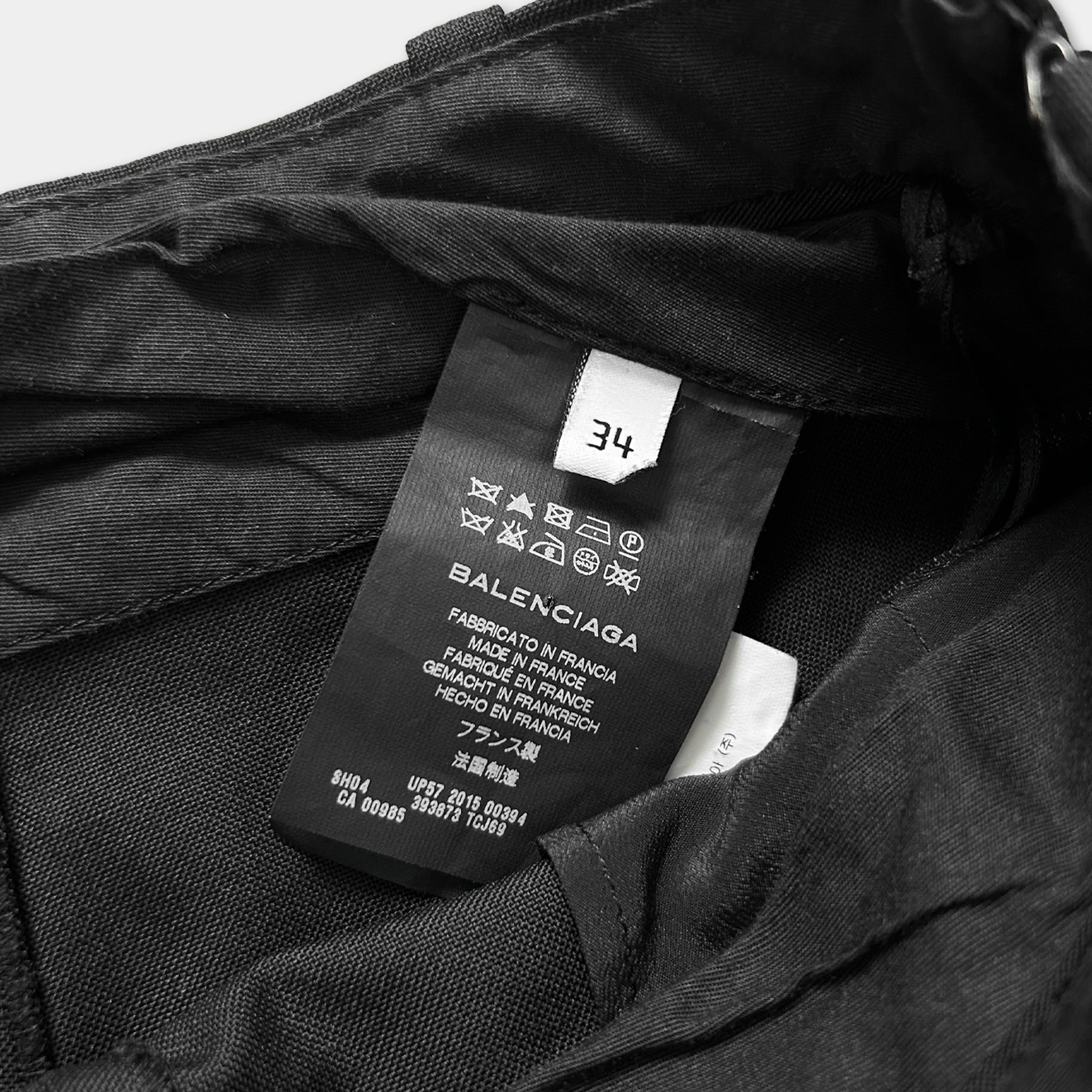A close-up view of a black fabric, possibly a piece of clothing, with a label attached to it. The label appears to be a garment label from Balenciaga, featuring various text and symbols.