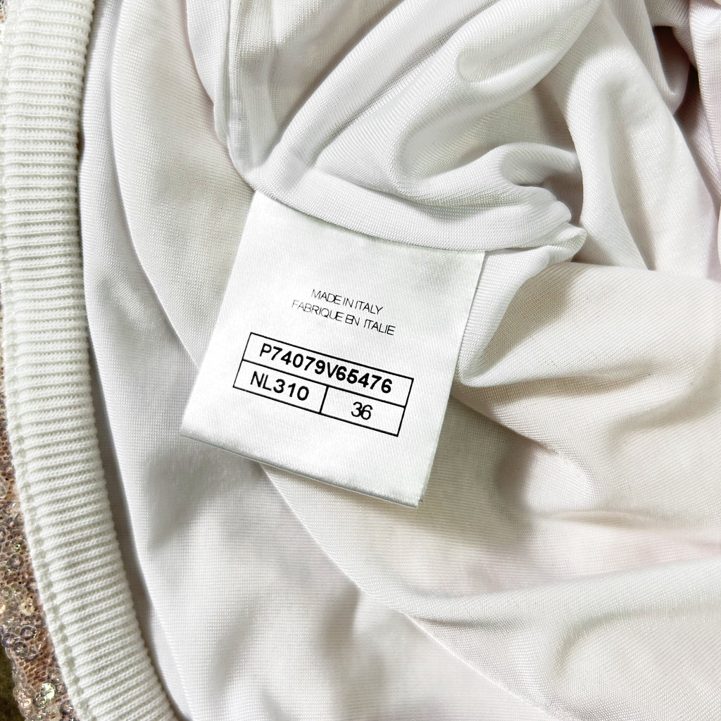 a close-up view of a white fabric, possibly a garment or textile, with a label or tag attached to it. The label appears to contain information about the fabric, such as the brand, material, and size.