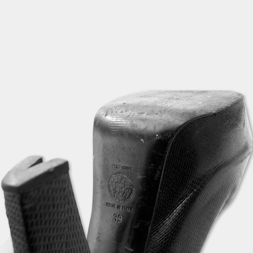 A close-up black and white image of a high-heeled shoe, showing the heel and sole.