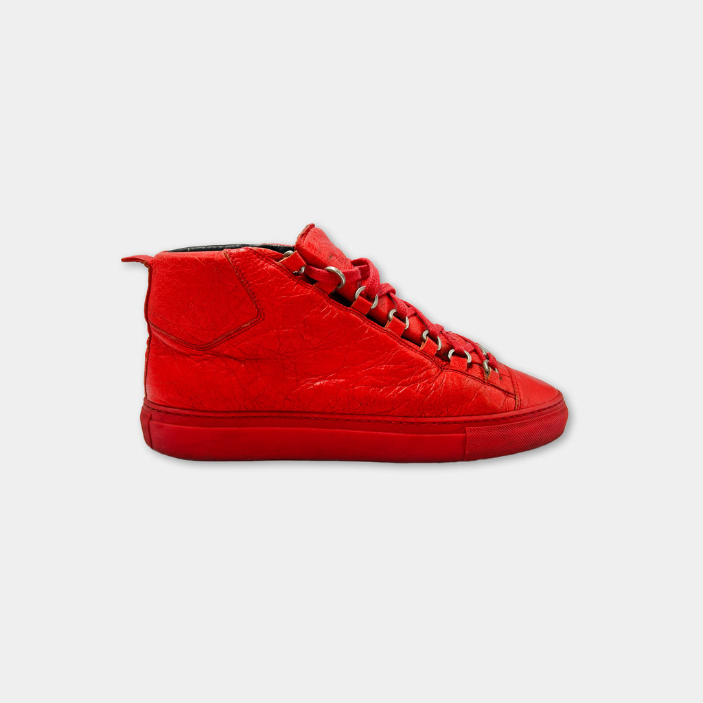 A bright red high-top sneaker with a red sole and laces.