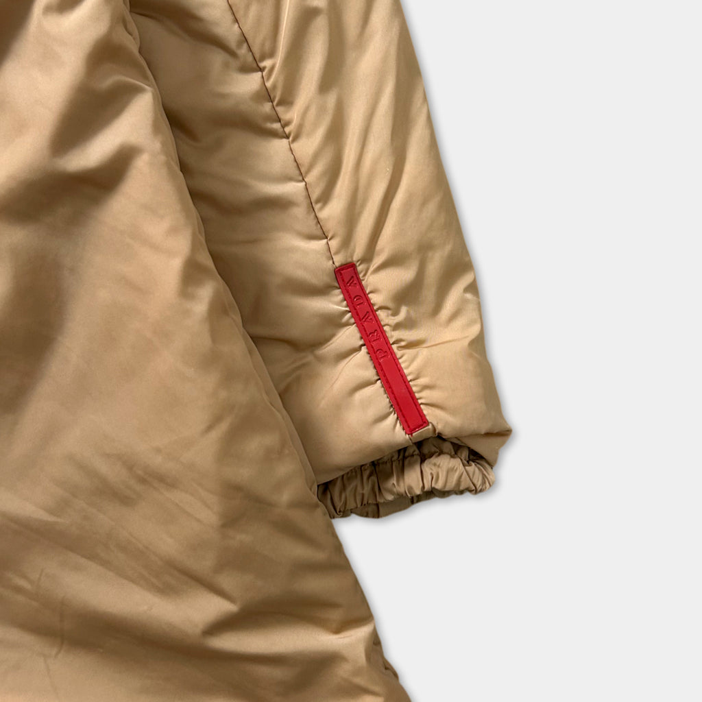 A close-up view of a beige jacket with a red zipper detail on the sleeve.