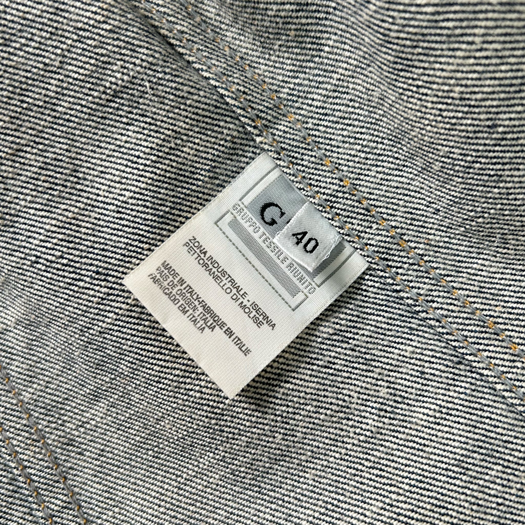 a close-up view of a denim fabric, with a label attached to it. The label appears to be a garment tag, likely indicating the brand, size, or other information about the clothing item.