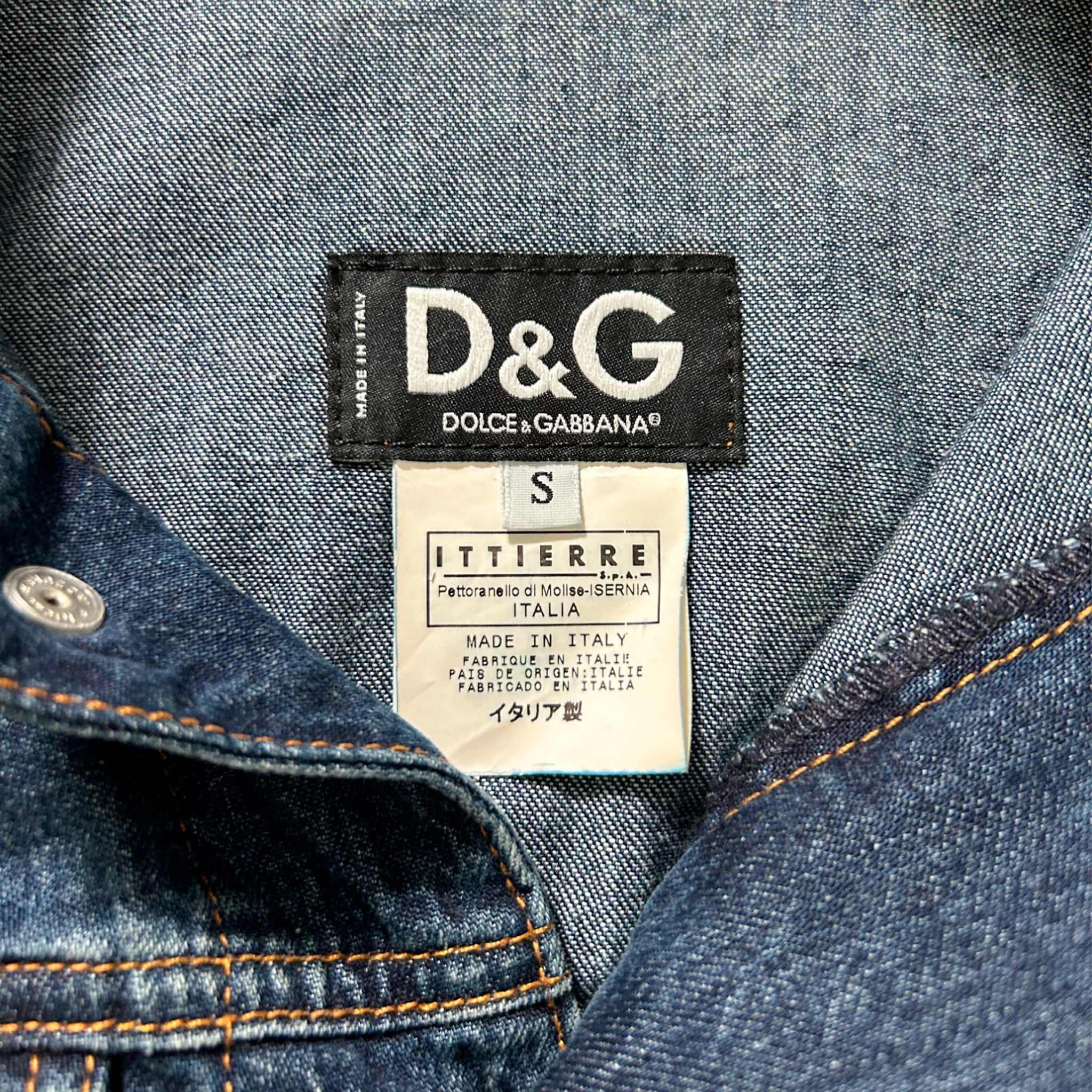 a close-up view of a denim jacket with a label attached to it, indicating the brand and size of the garment.