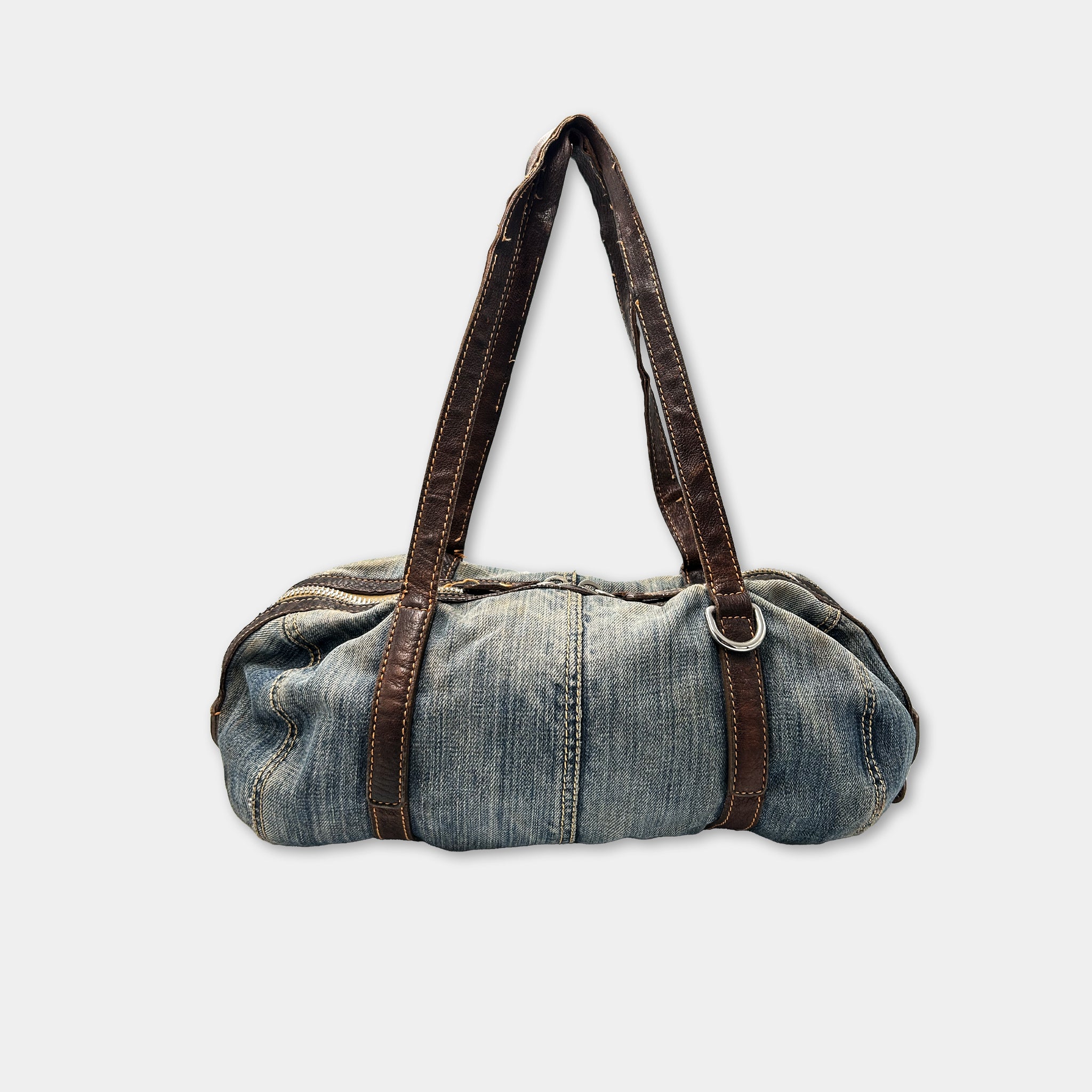 A blue denim bag with brown leather straps and buckles.